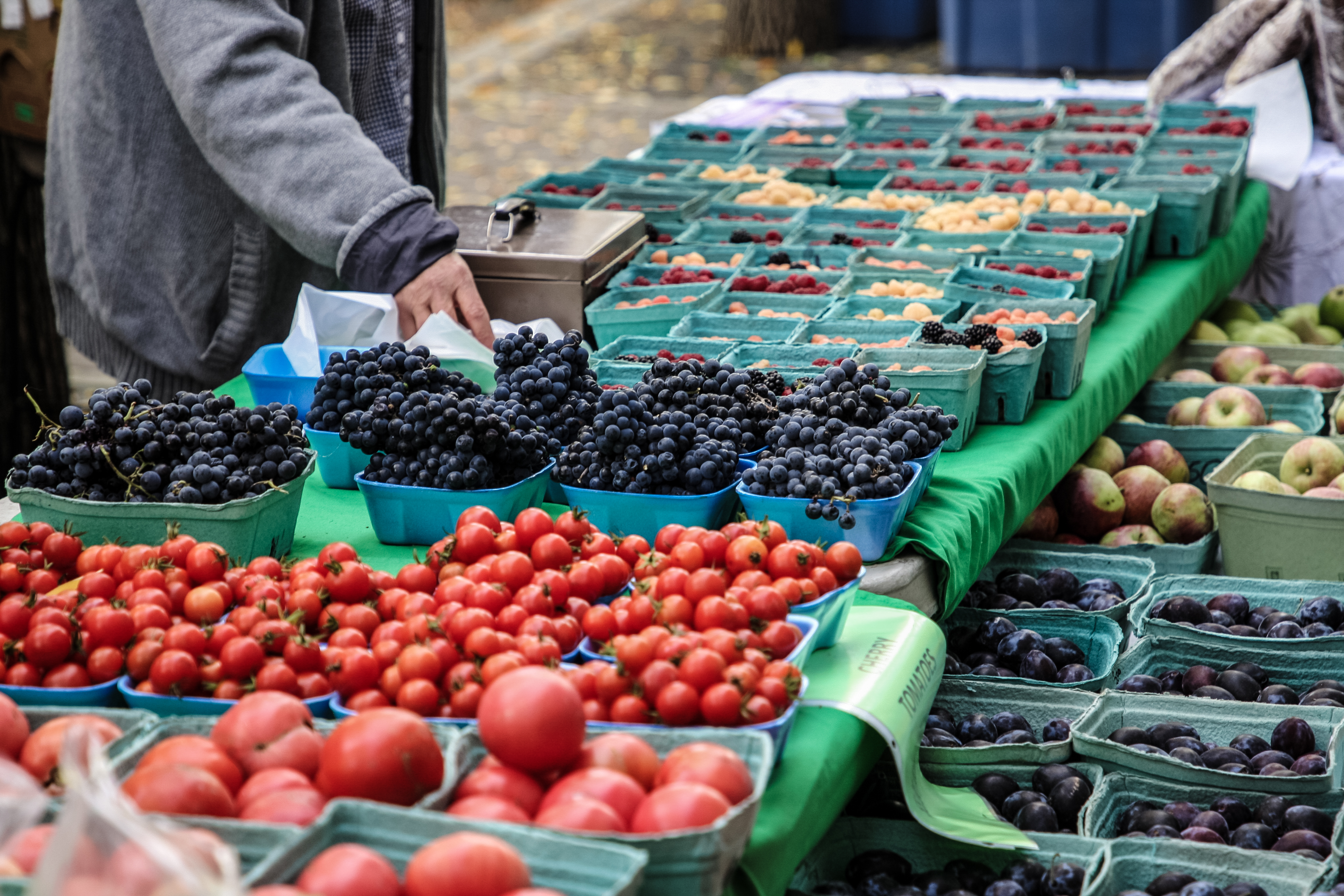 Cartons of tomatoes, blueberries and fruits on an outdoor stand at the Kamloops Farmers Market