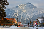 Shops and restaurants on a street in Banff town, with snow-covered mountains behind
