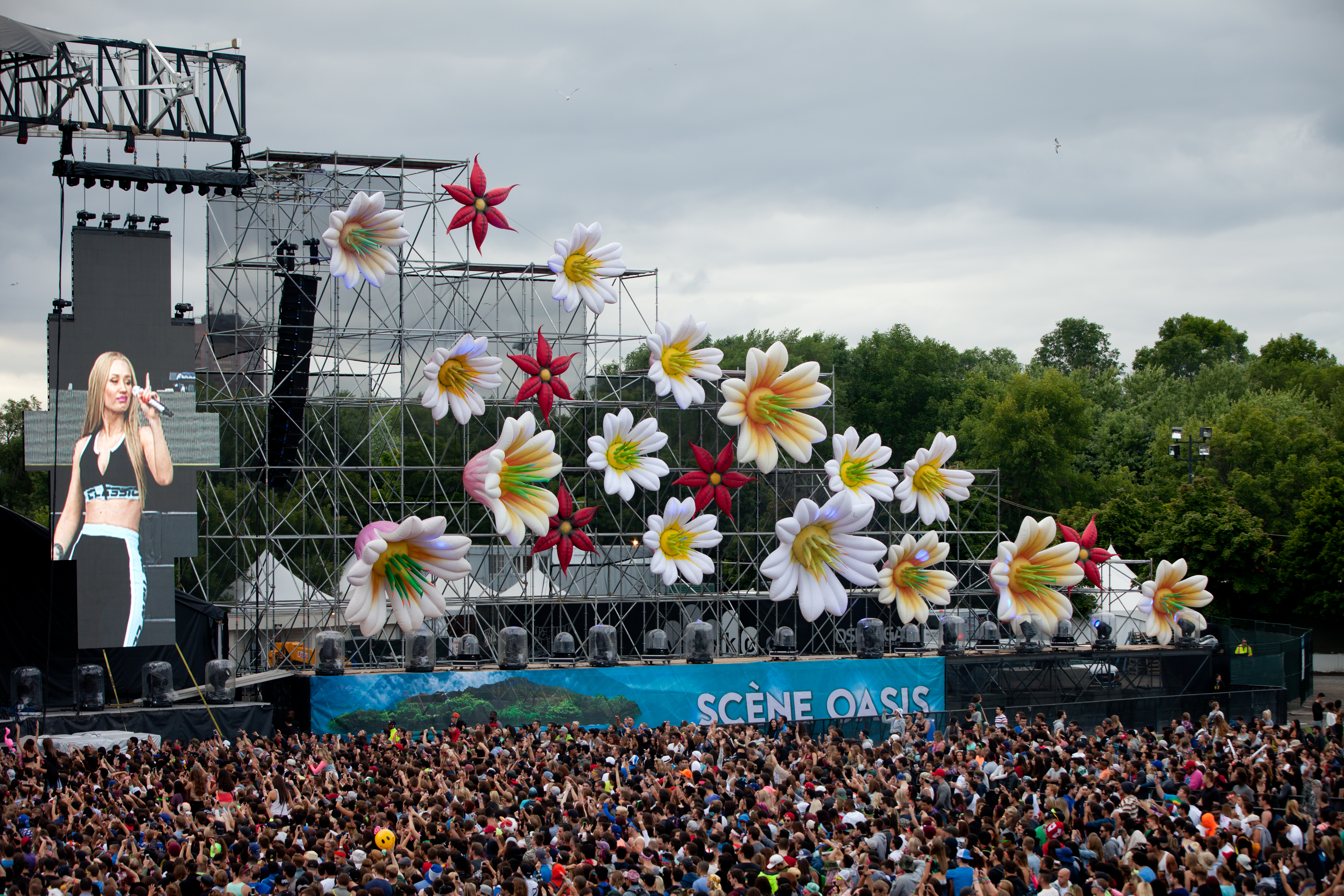 A flower art installation next to a stage with a large screen displaying a singer