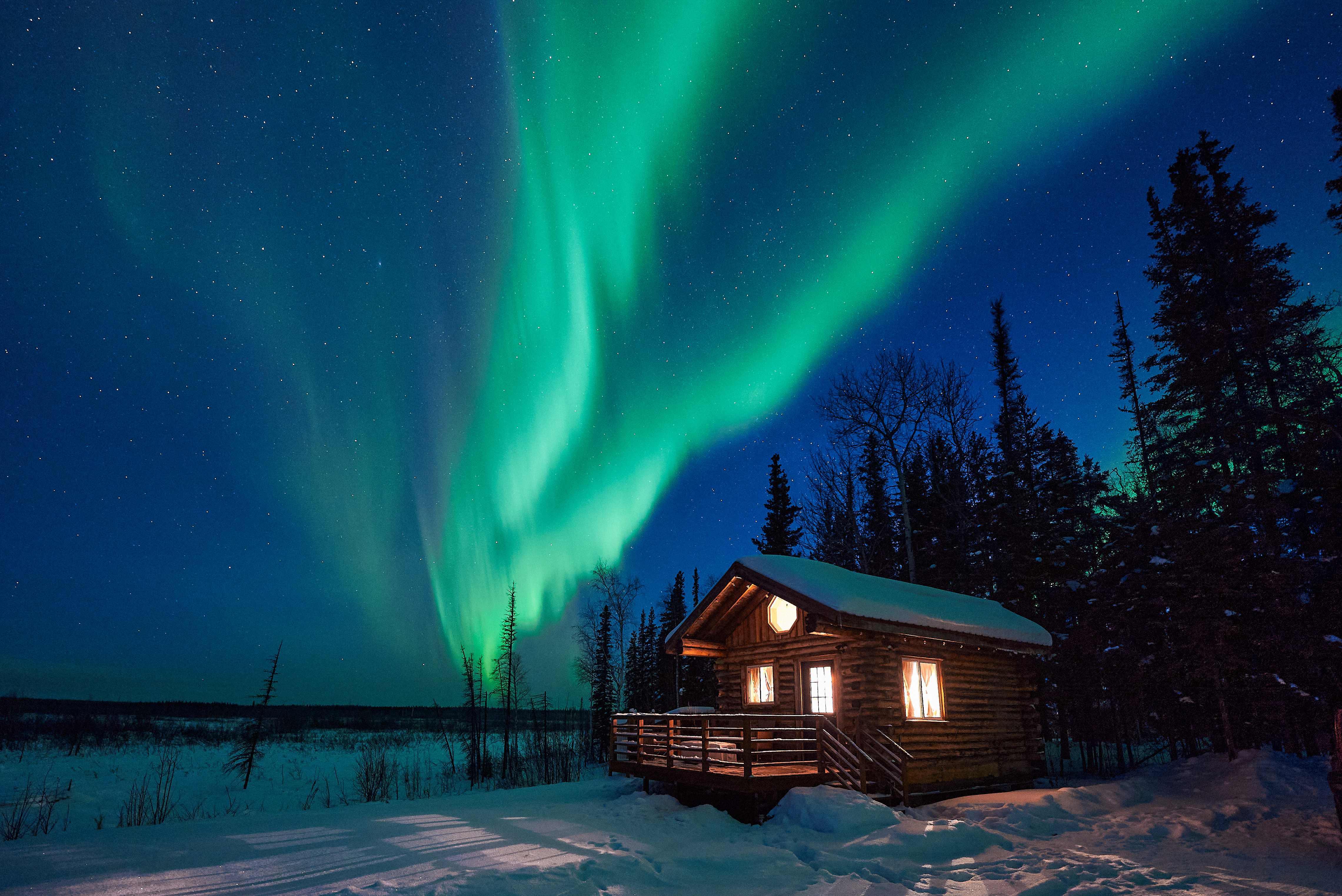 Lights illuminate the cabin in the snow