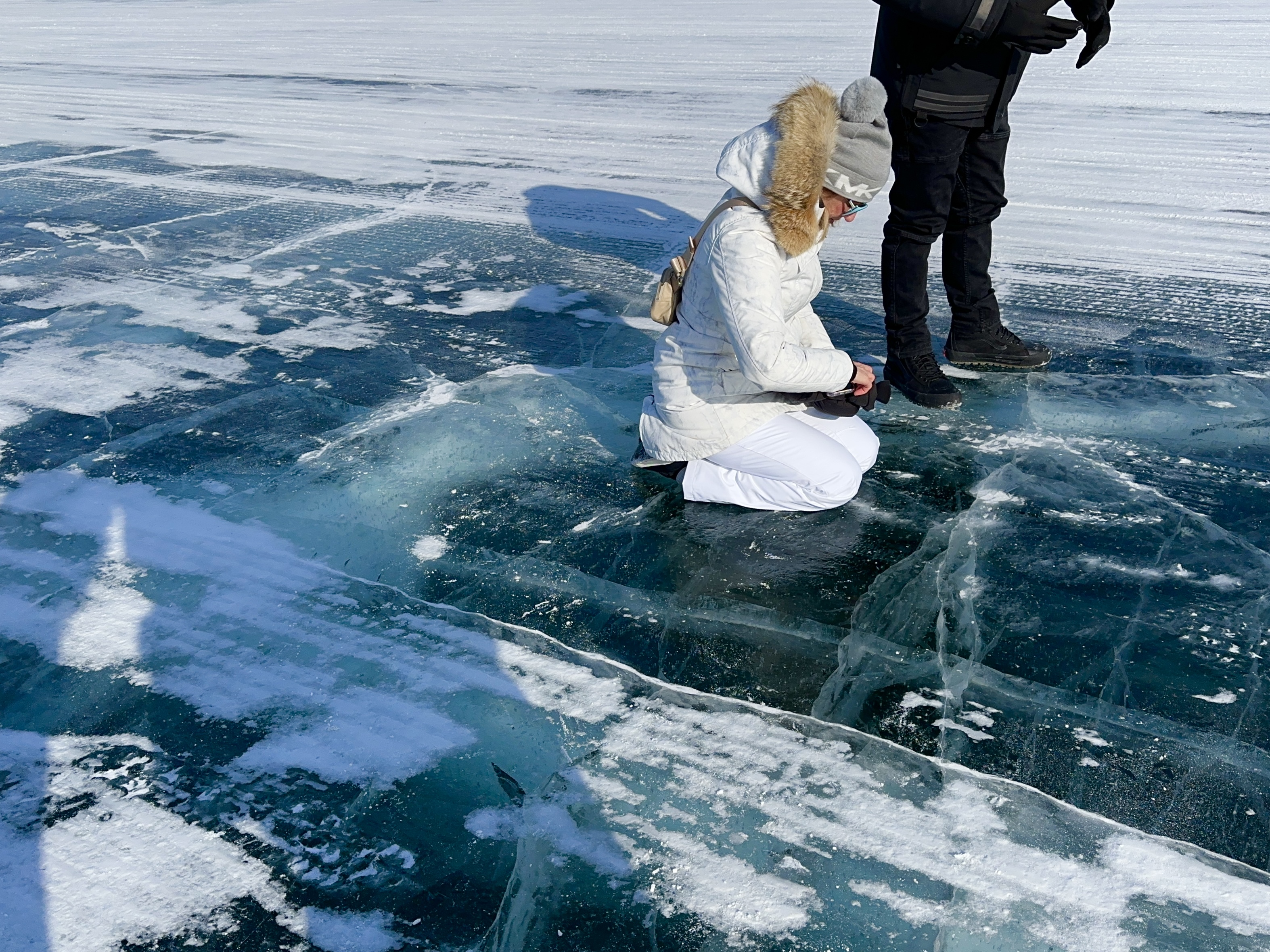 A man and a woman are kneeling on a piece of ice road