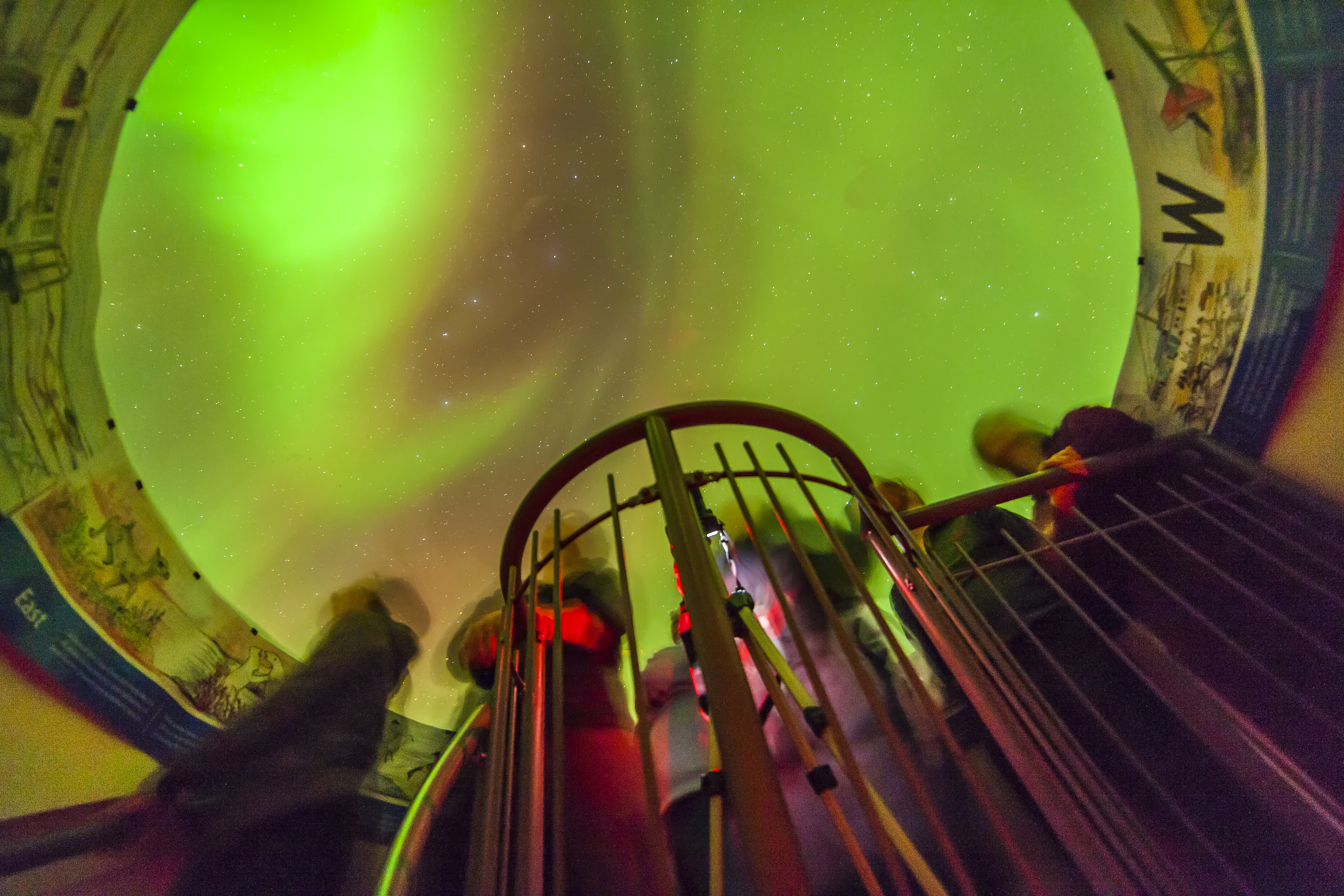 People looking at the Northern Lights from the indoor viewing dome at the Churchill Northern Studies Centre
