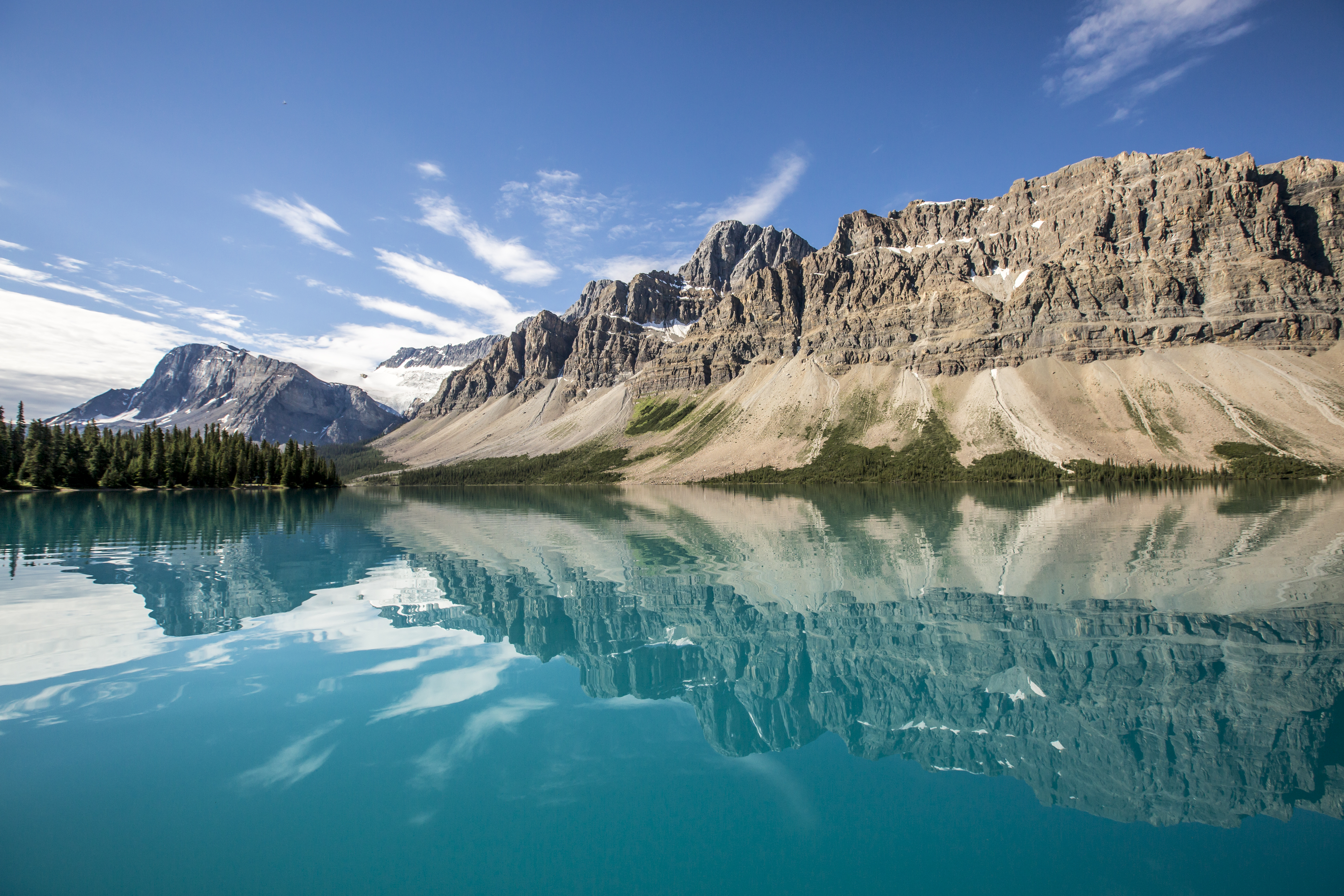 Large turquoise glassy glacial lake near glacier and Mount Gordon in Banff National Park
