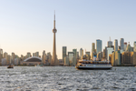 Ferry in Toronto’s Inner Harbour passes by city skyline at sunset