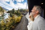 A couple stands on the Goldleaf outdoor viewing platform on a Rocky Mountaineer train