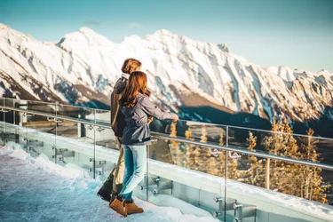 A couple takes in the view from a platform at the top of Banff Gondola