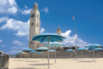 Sandy beach with blue umbrellas, stairs and a clocktower