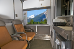 A VIA Rail sleeper train cabin has two chairs next to a window looking out to the Rockies
