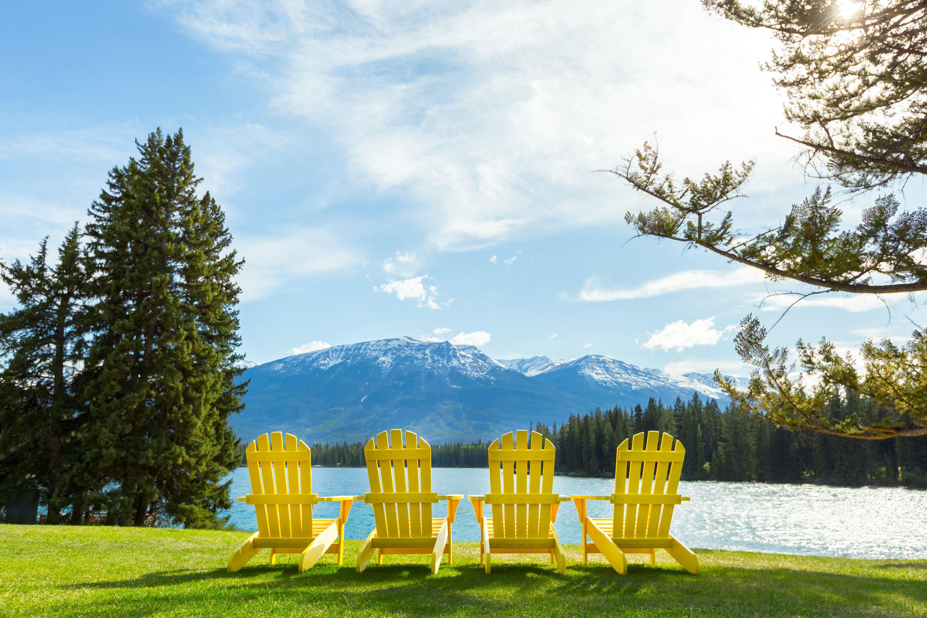 A line of yellow chairs on the lawn in front of Lac Beauvert at Jasper Park Lodge.