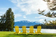 A line of yellow Adirondack chairs perched on the lawn in front of Lac Beauvert at Jasper Park Lodge.