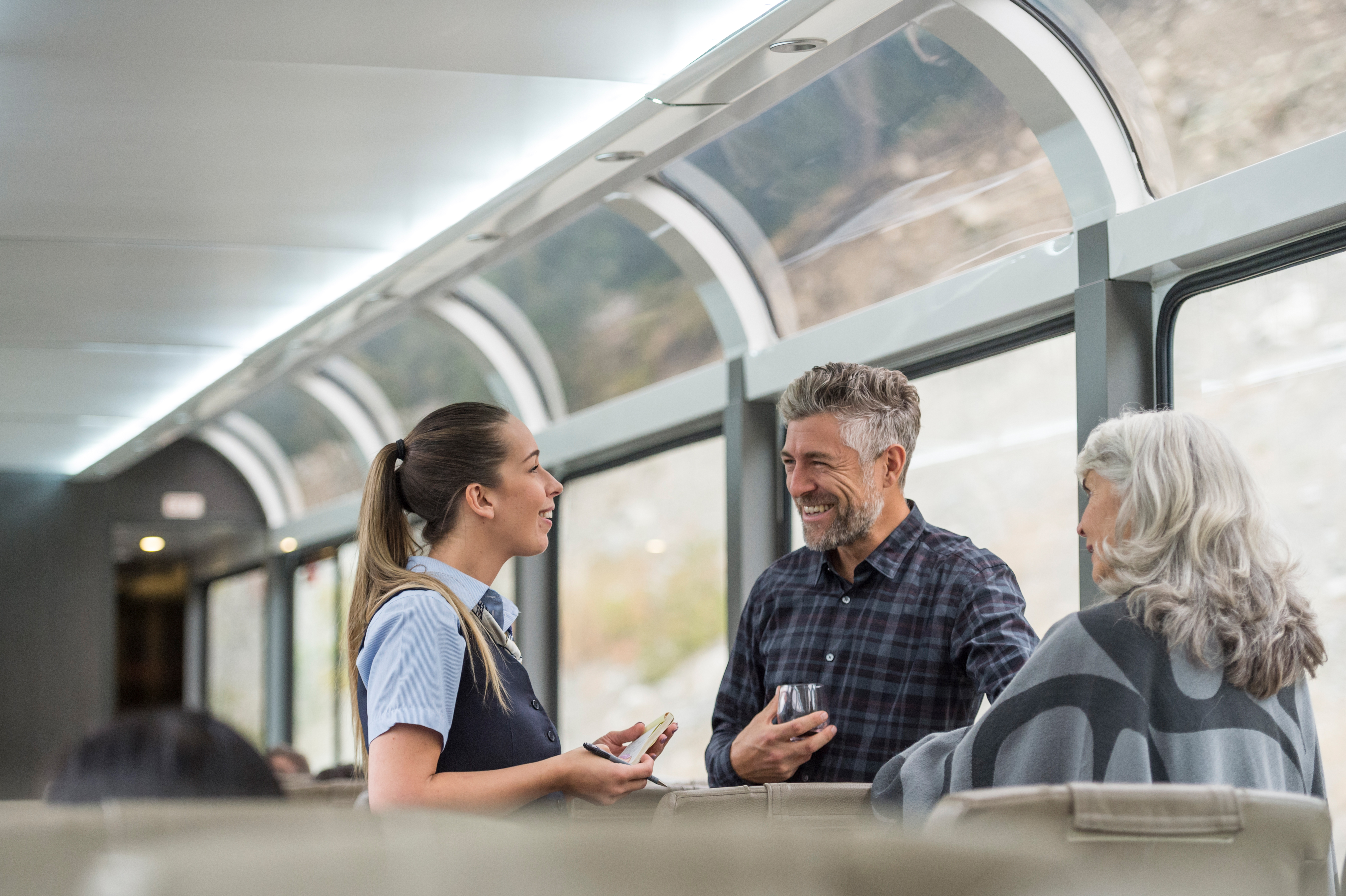 Onboard host taking meal order from guests on the SilverLeaf coach of the Rocky Mountaineer train