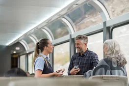 Onboard host taking meal order from guests on the SilverLeaf coach of the Rocky Mountaineer train