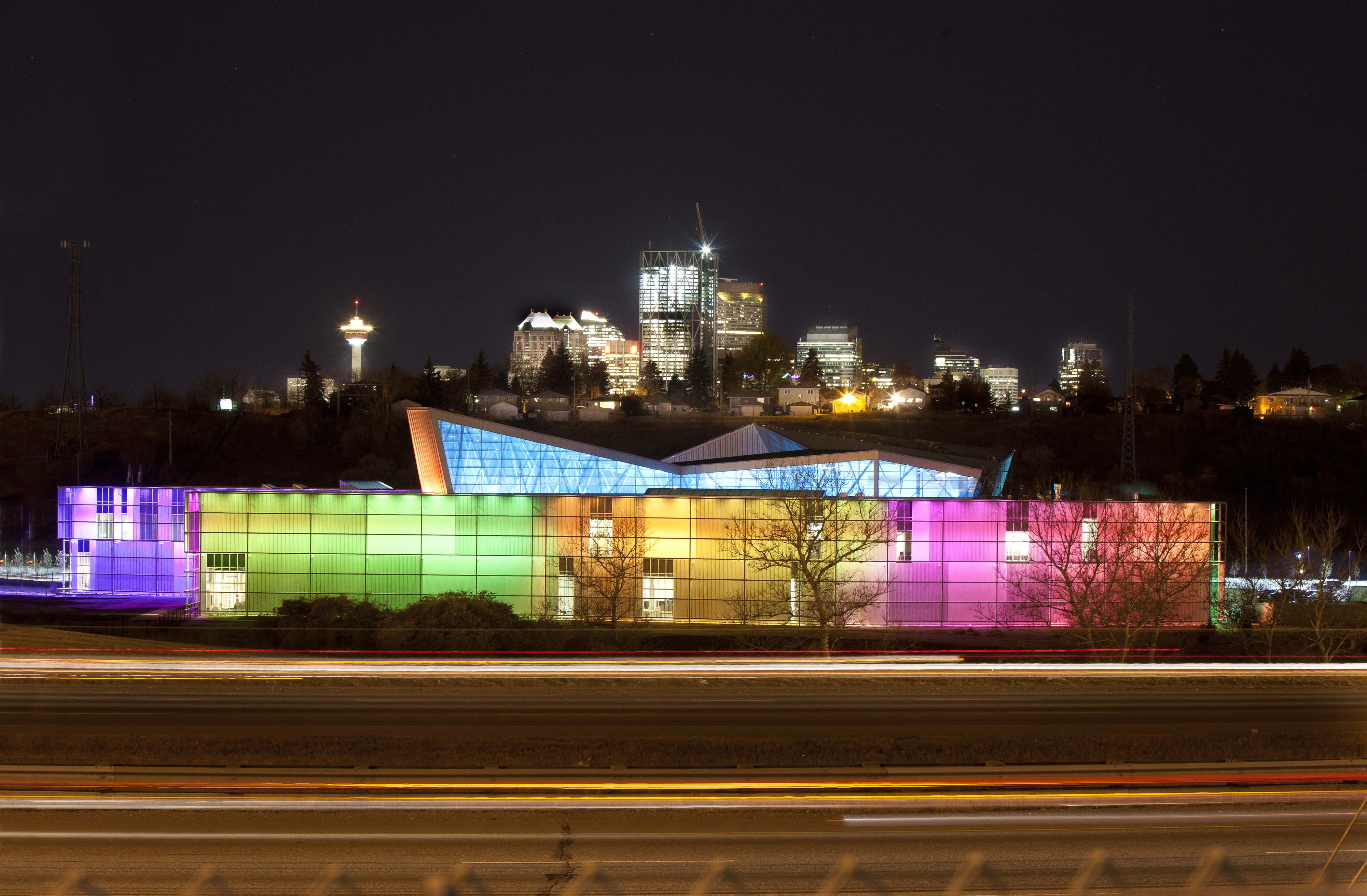 TELUS Spark colourful building exterior at night with Calgary skyline in the background