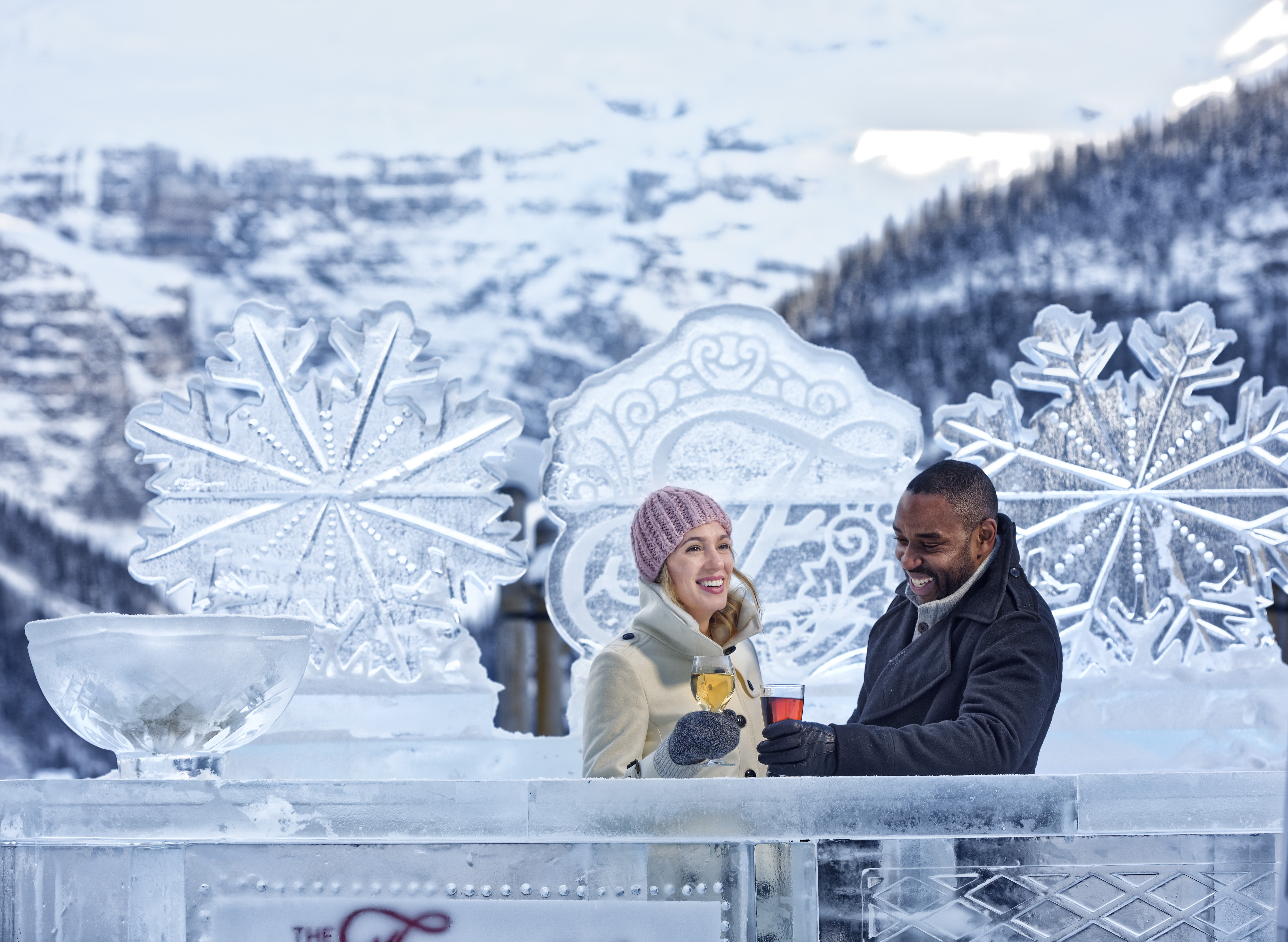 Couple cheersing on frozen Lake Louise with ice sculpture