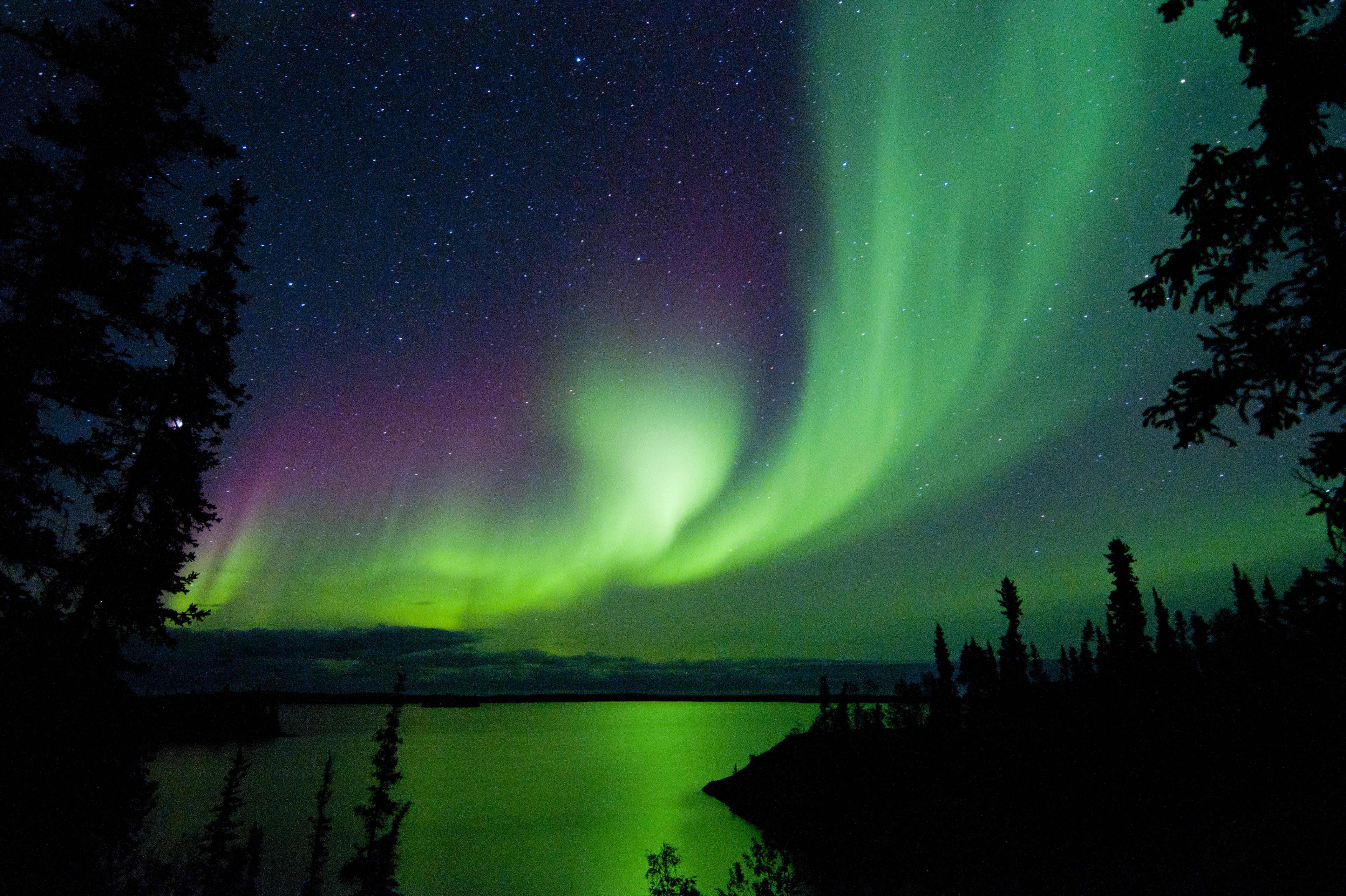 Impressive Aurora display spreads across starry sky and above body of water in Canada’s Northwest Territories 