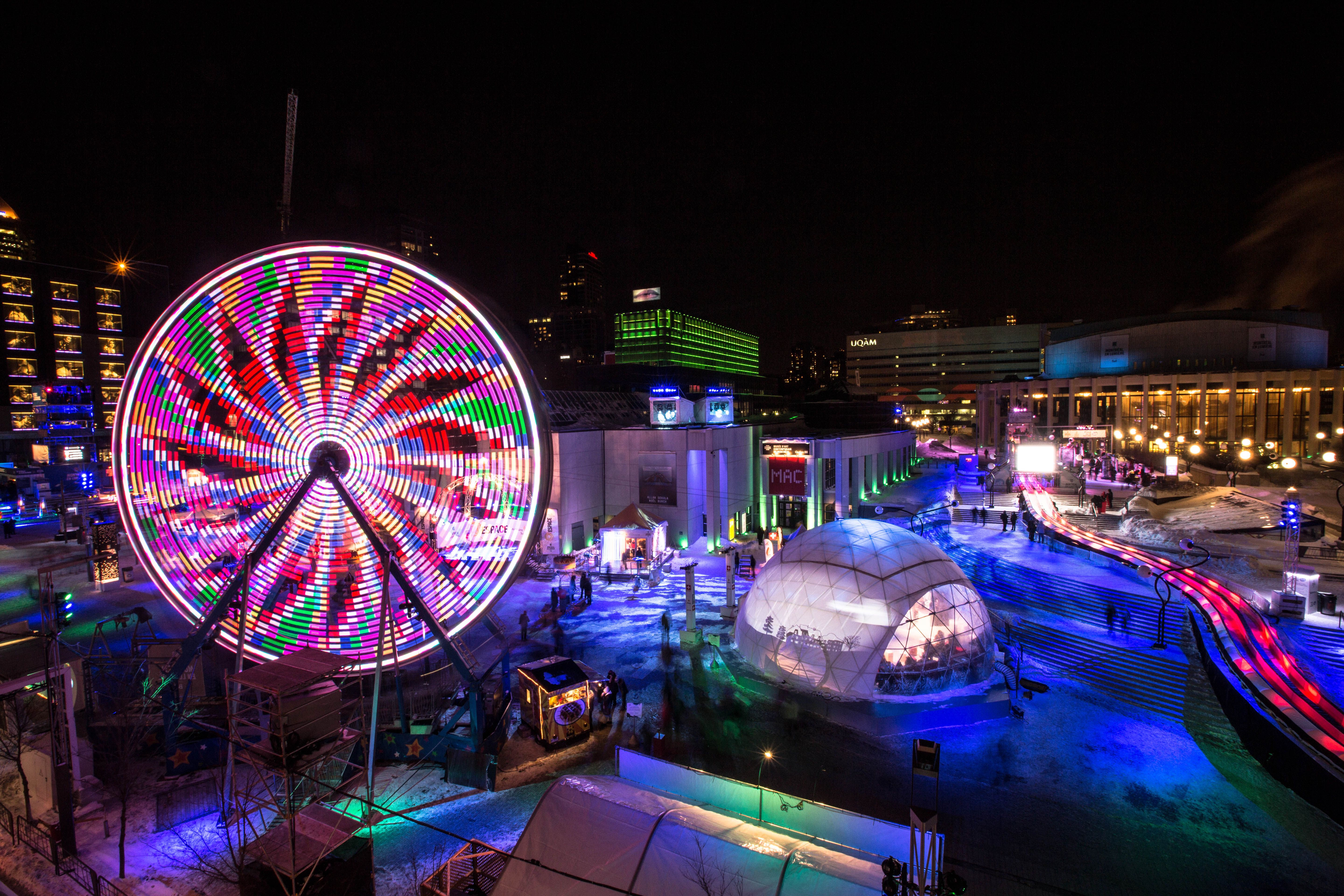 Colourful light wheel and winter entertainment area at night during the Montreal en Lumiere festival