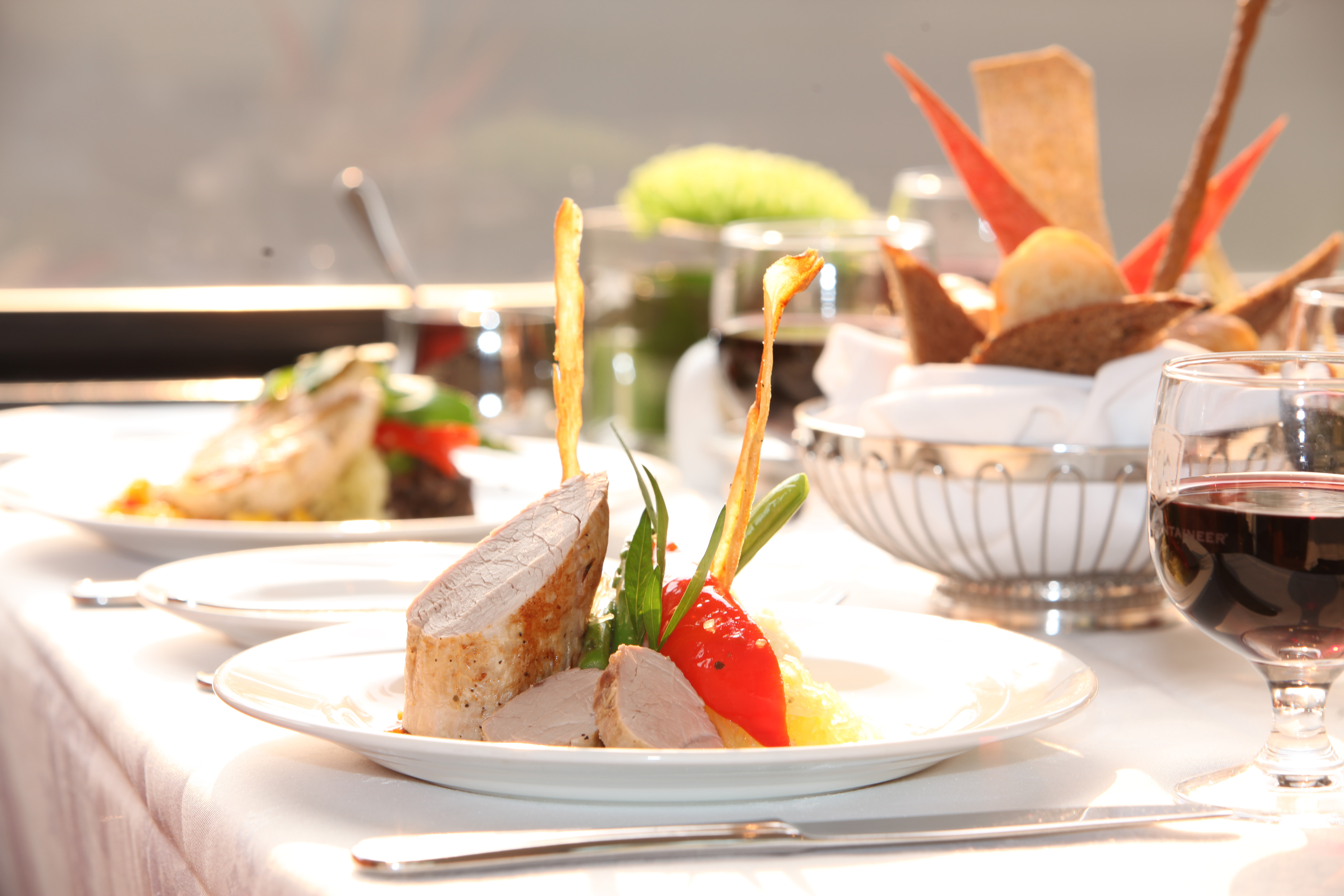 Alberta Pork Tenderloin is served alongside a glass of red wine in GoldLeaf Dining car onboard the Rocky Mountaineer.