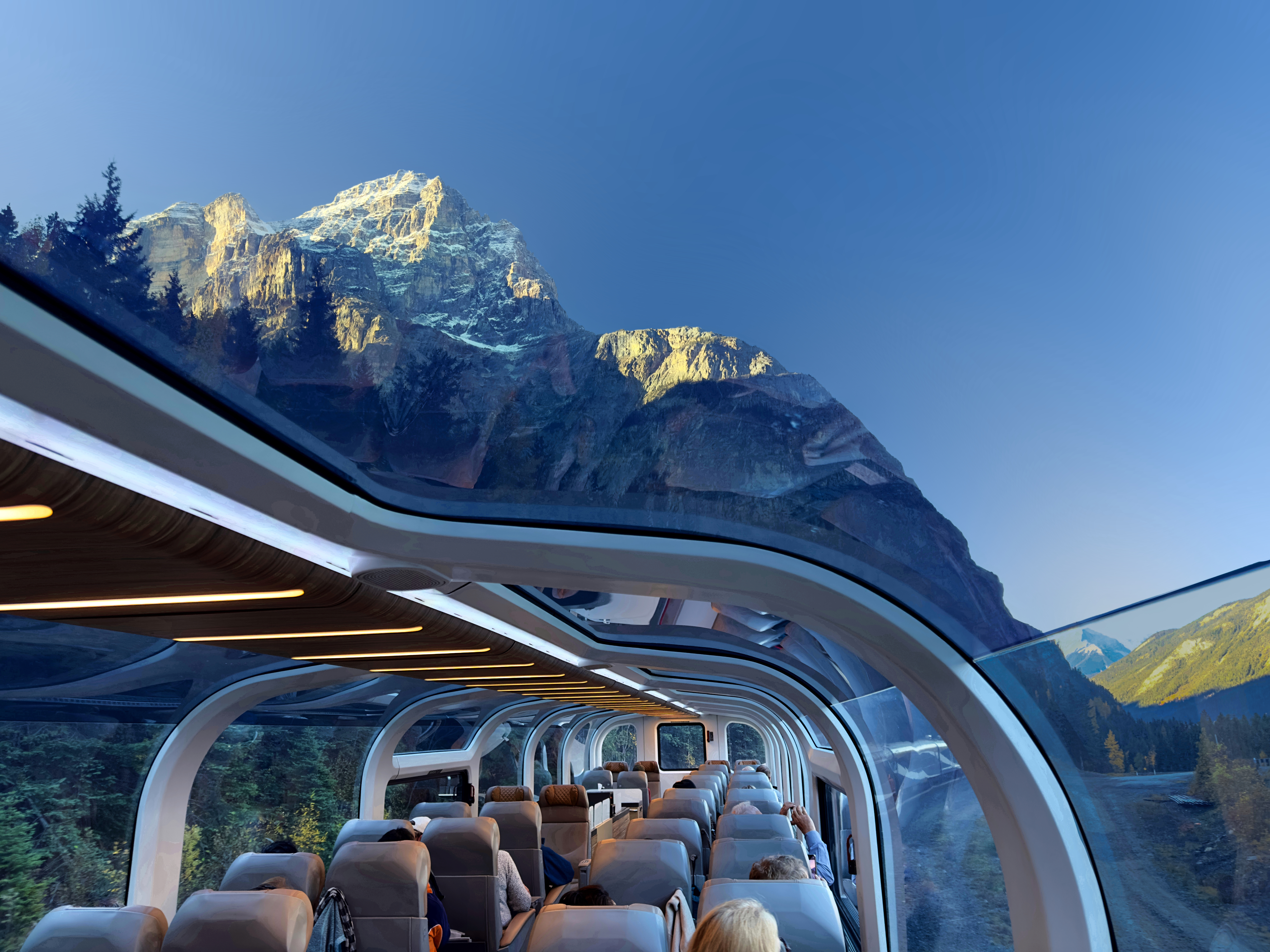 Close-up POV shot looking out through a glass-topped train onto majestic snowcapped mountains of the Canadian Rockies
