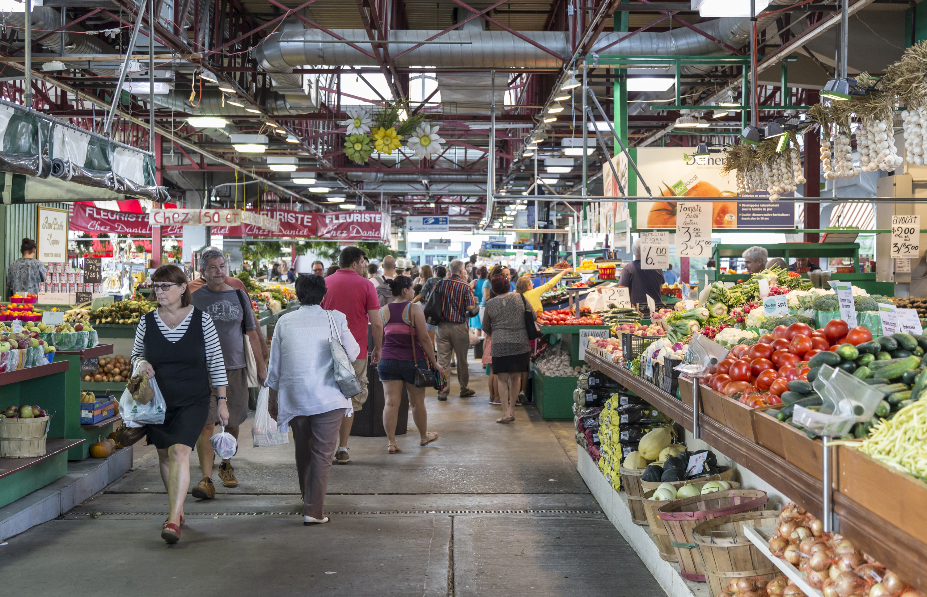 People walk past vegetable stands in the Jean-Talon Market