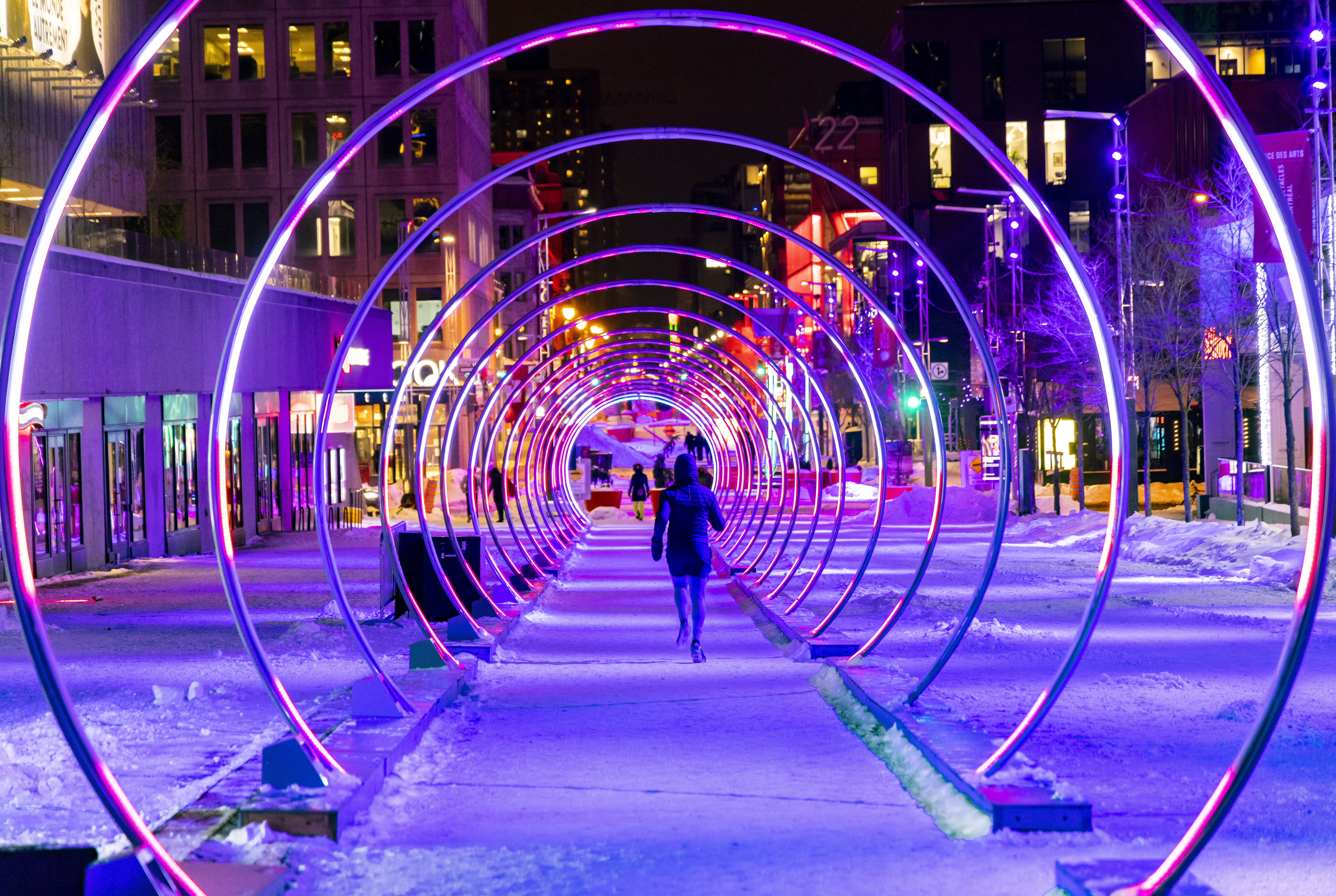 Person walks through an interactive outdoor light tunnel at night