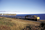 VIA Rail train travels along coast and past villages during daytime
