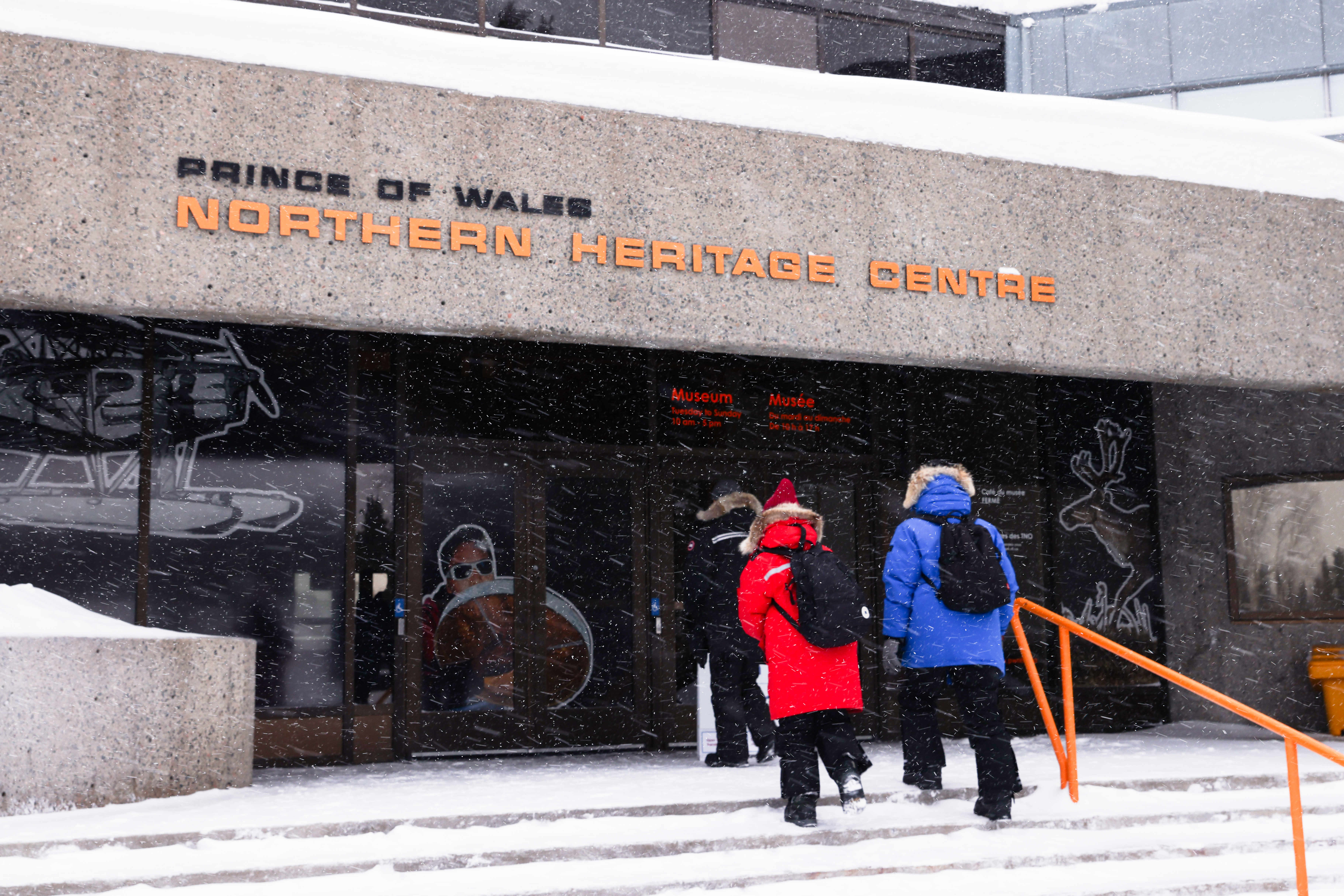 A group of people are walking into the prince of wales northern heritage center