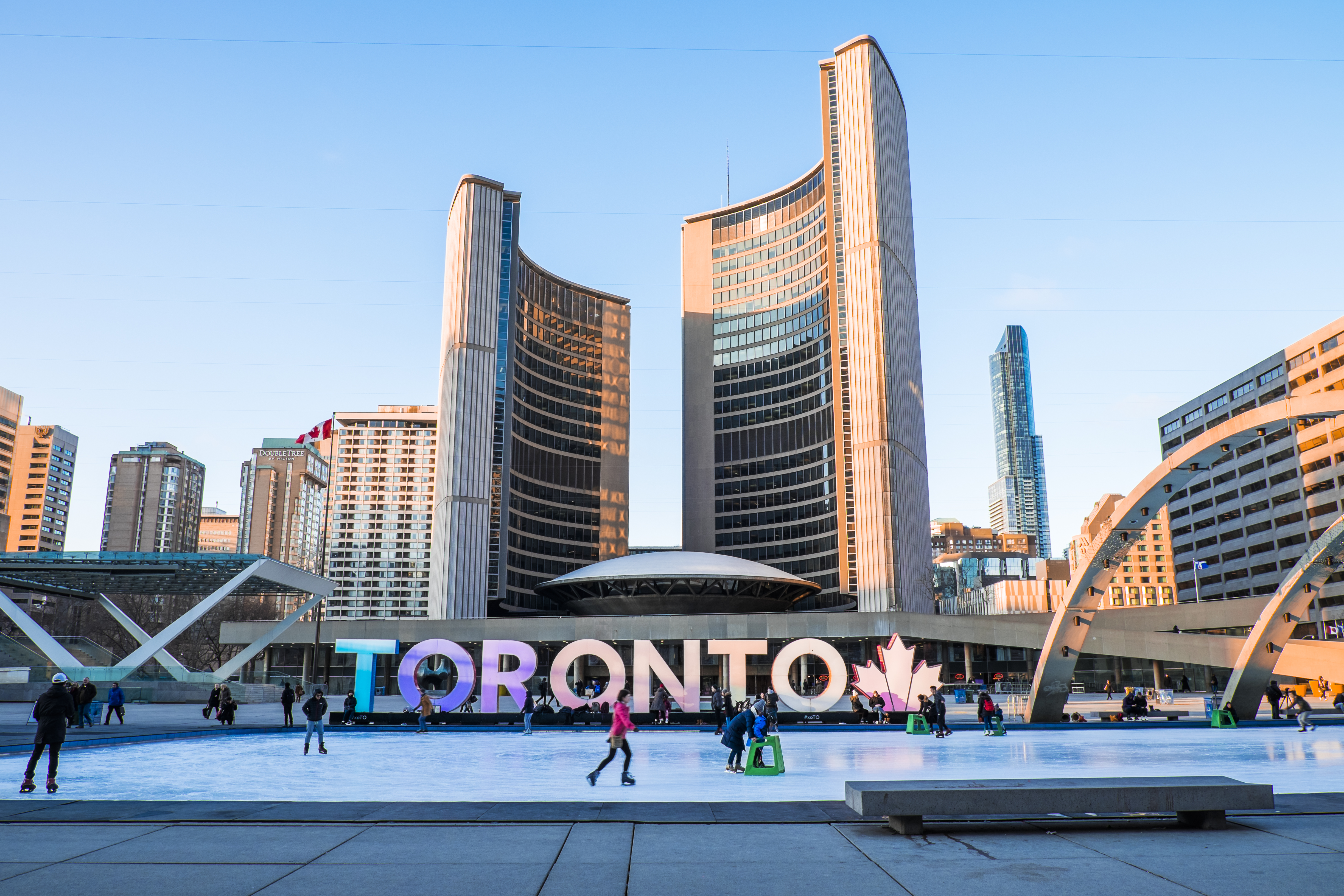 People skate at Nathan Phillips Square in front of the Toronto Sign in winter