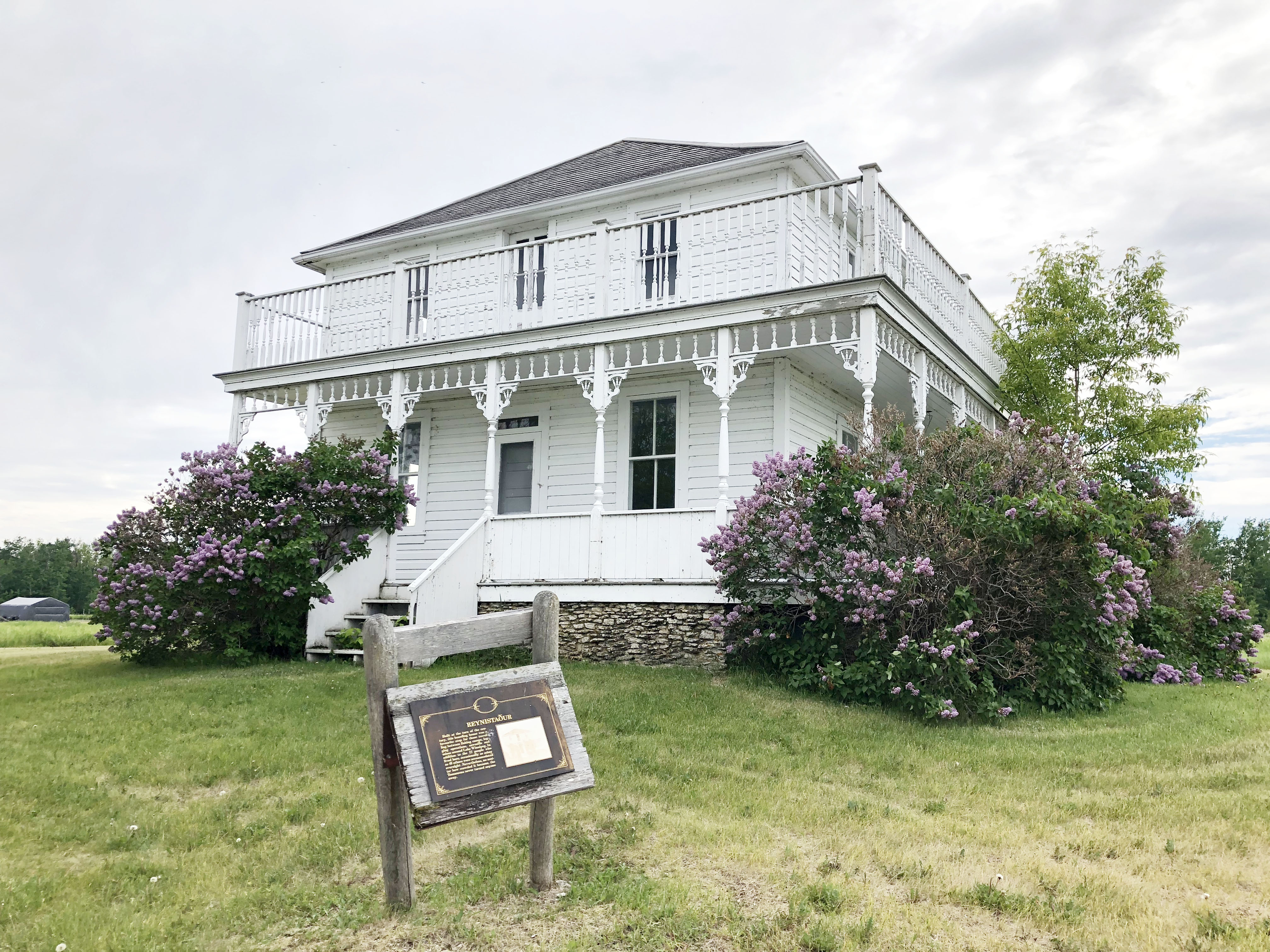 Info board in front of a white heritage building on Hecla Island