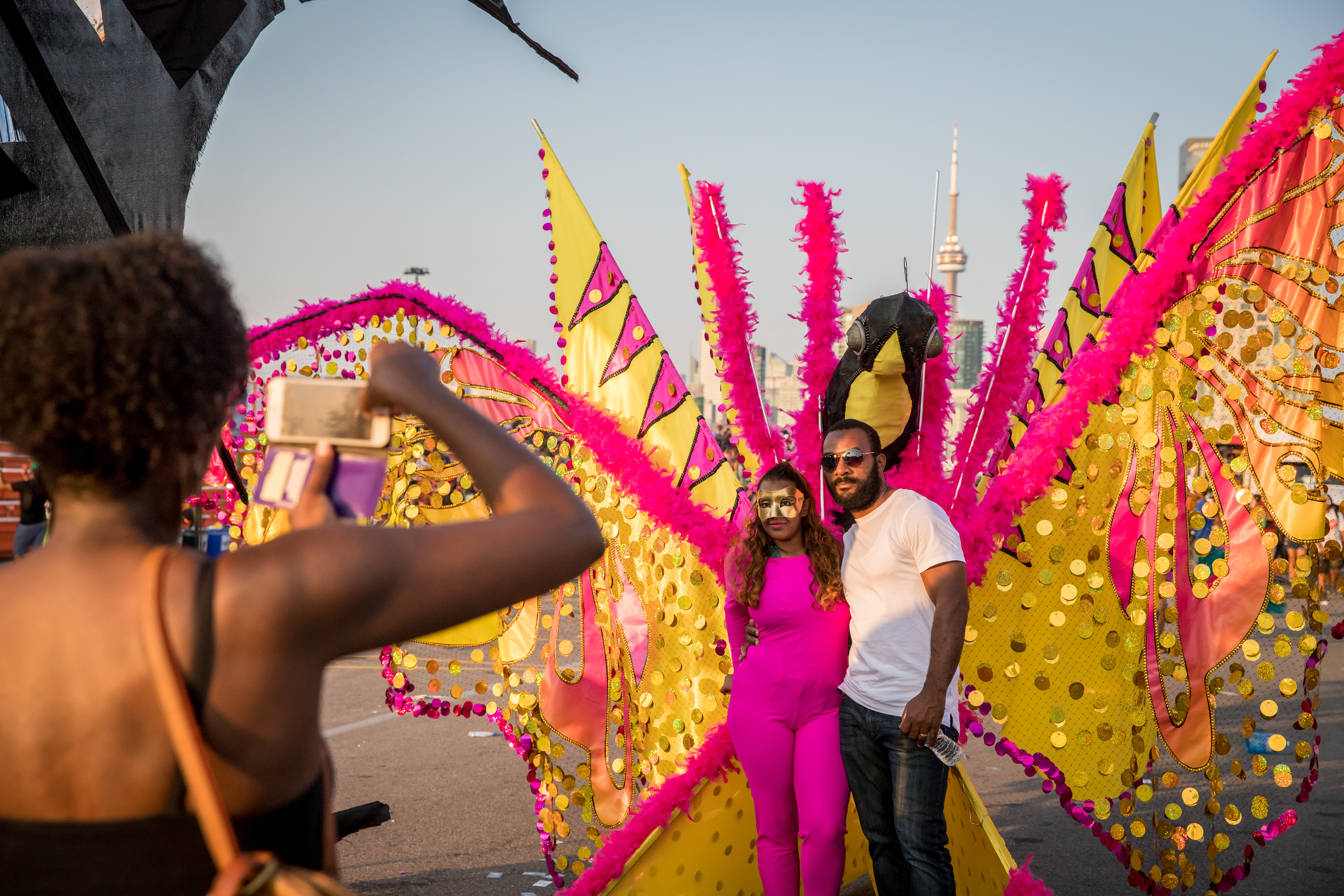A man stands next to a woman in a pink and yellow carnival costume