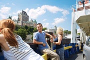 A young man leans against the side of a ferry as it cruises past the Fairmont Chateau Frontenac in Quebec City.