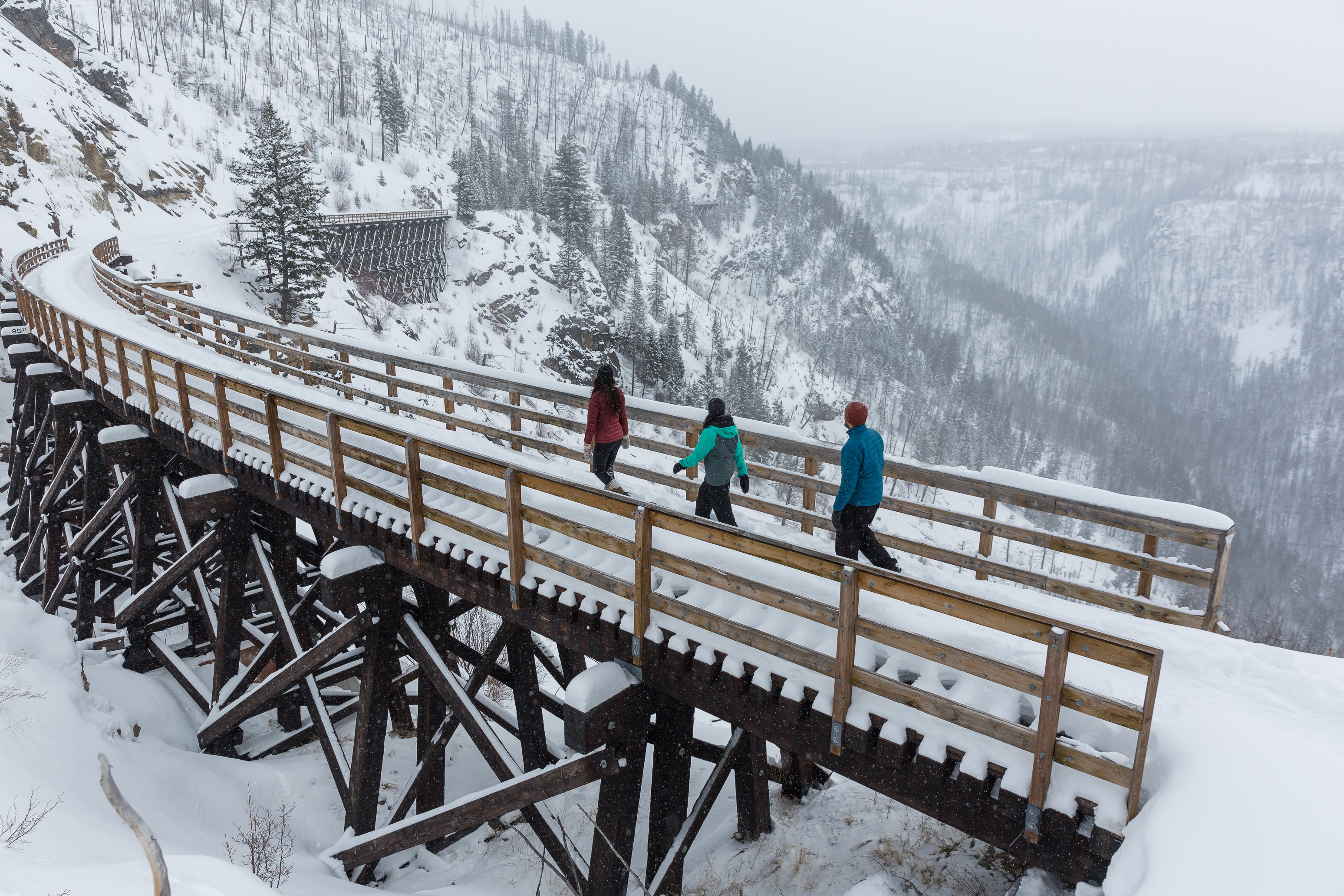 People walking across a trestle bridge in the snow