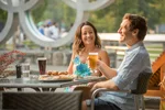 Couple enjoys a meal on a restaurant patio in front of the Olympic rings in Whistler