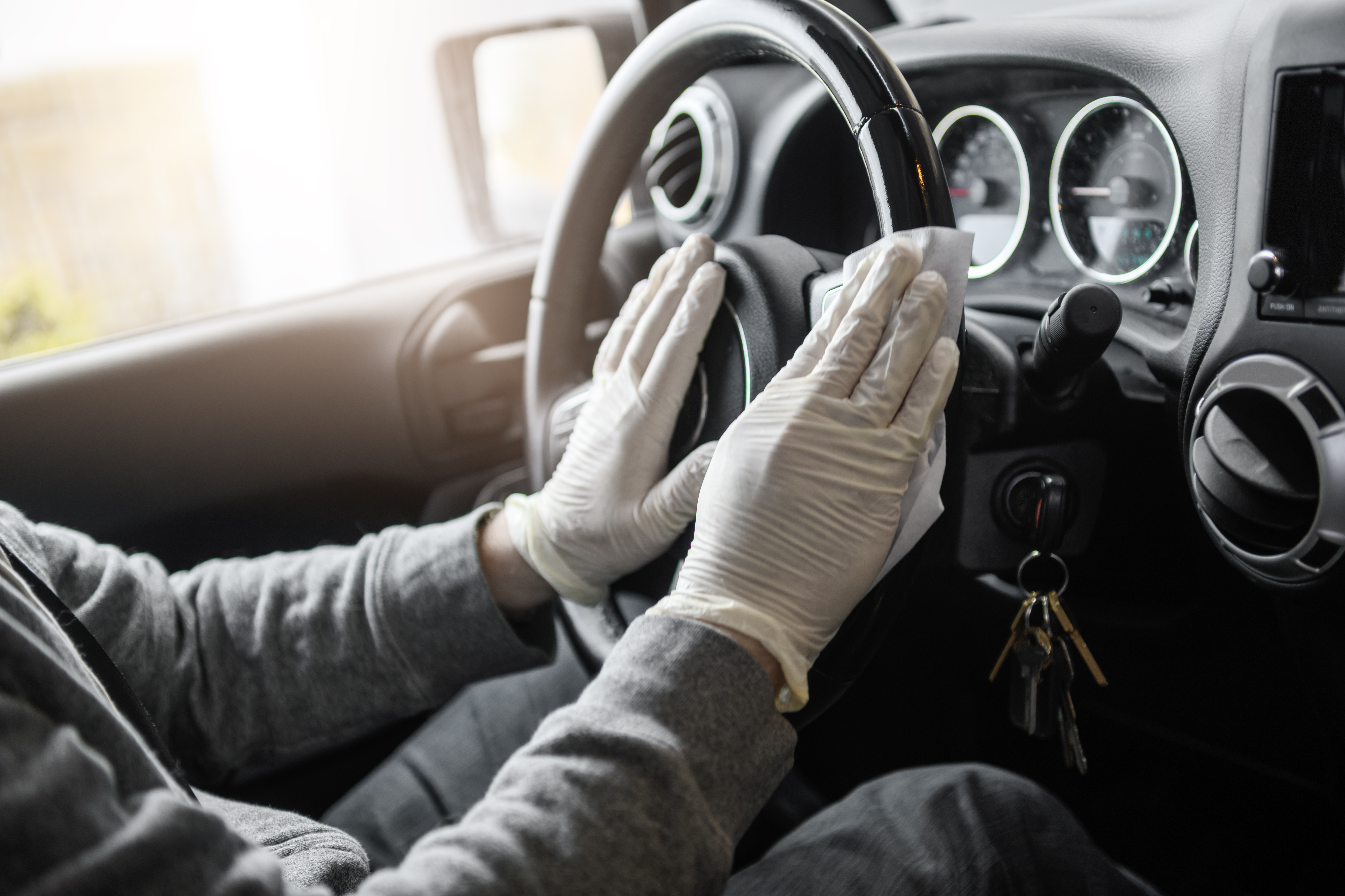 man wiping down car steering wheel