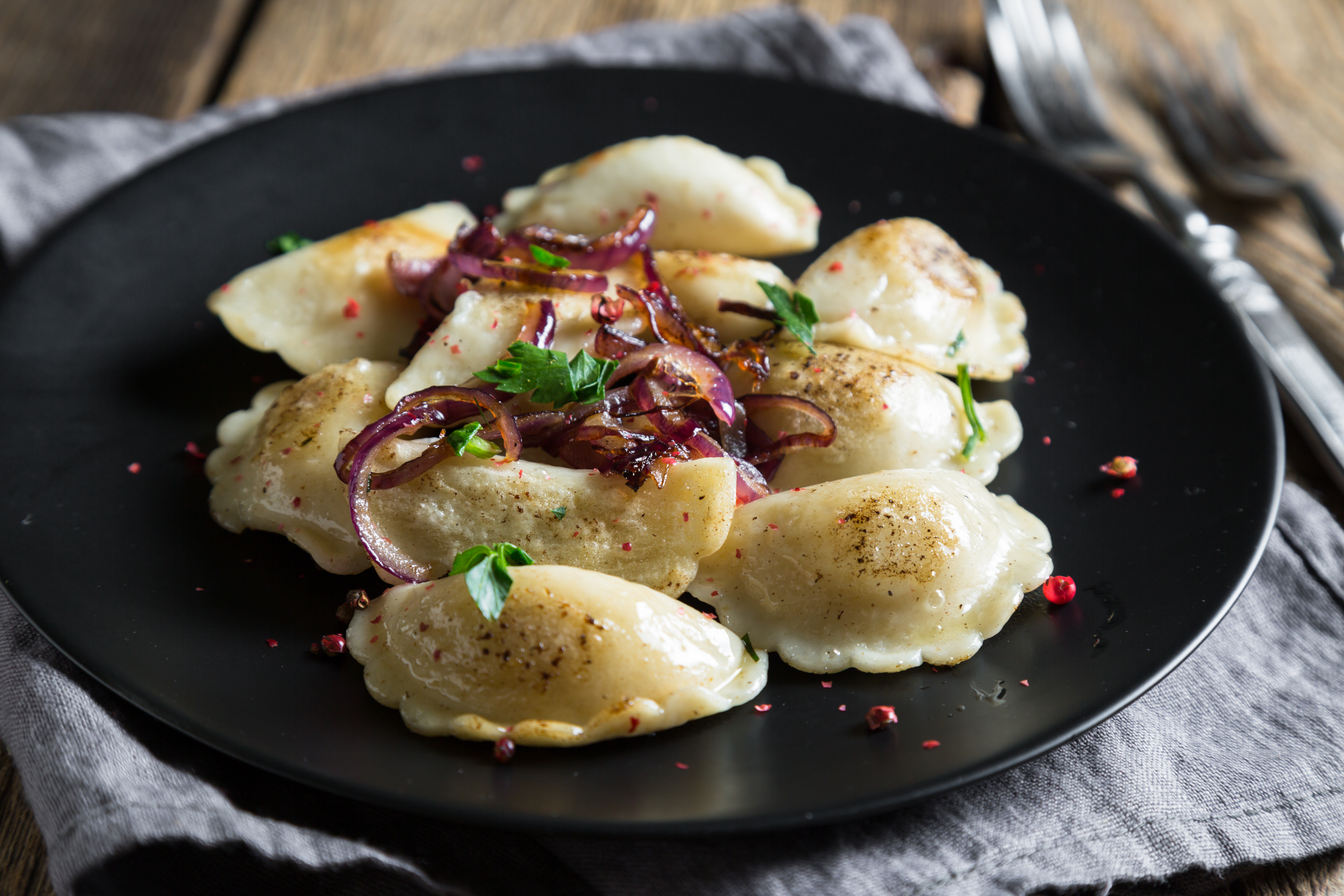 A plate of Pierogies garnished with red onion and herbs