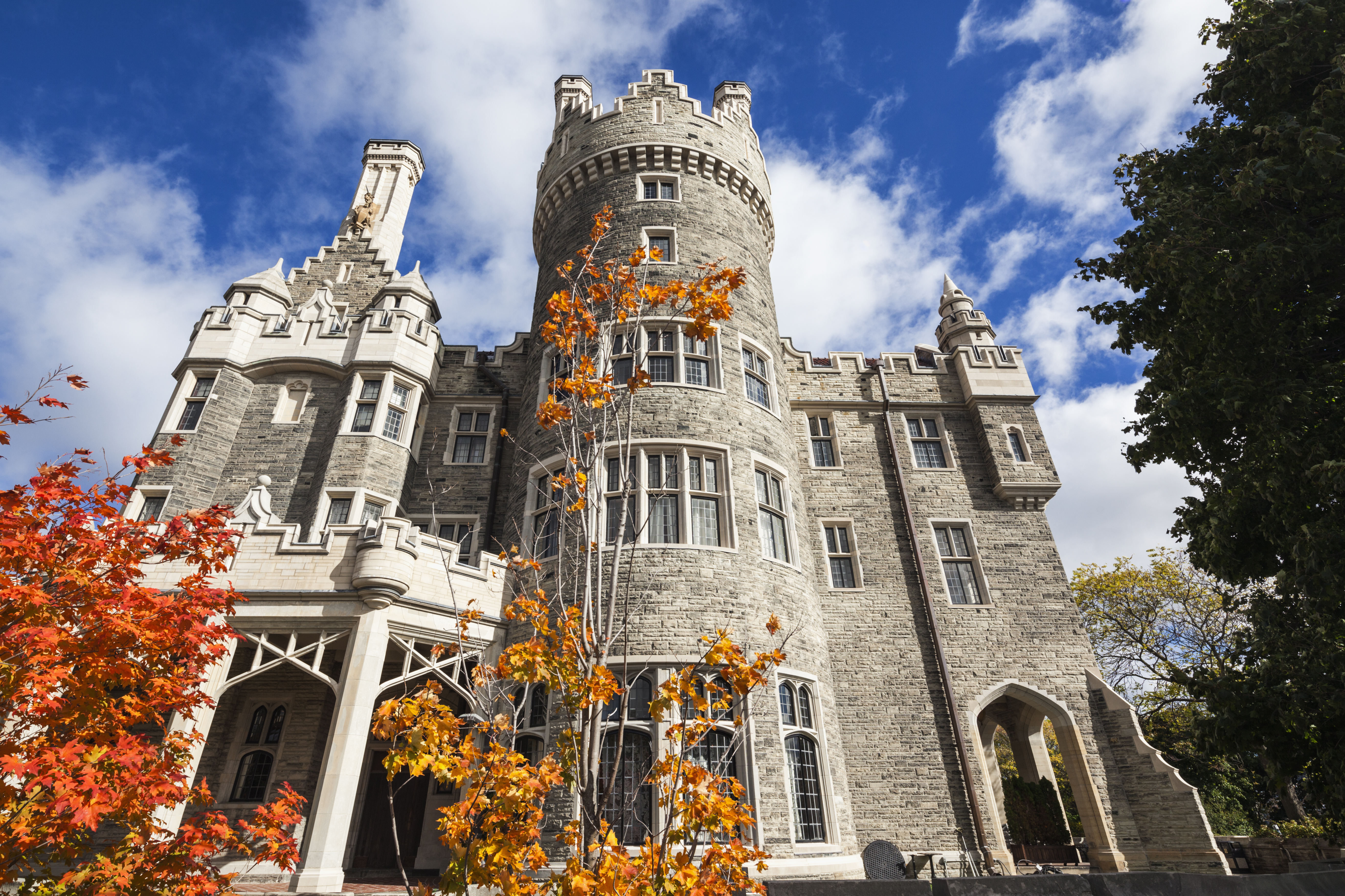 Exterior of castle and fall foliage stand out against a blue sky
