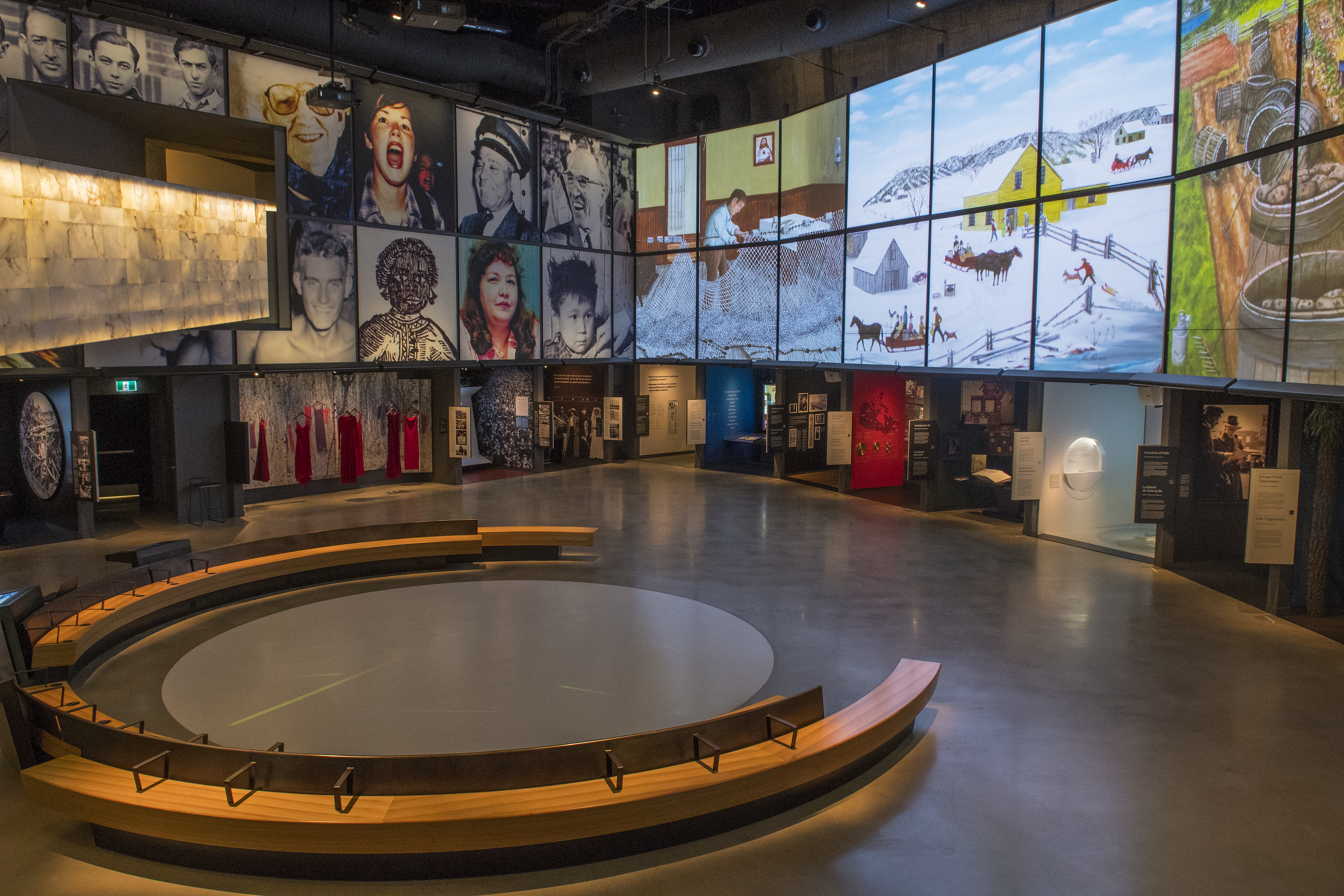 Circular bench in the middle of an exhibition hall with photos of faces on the wall