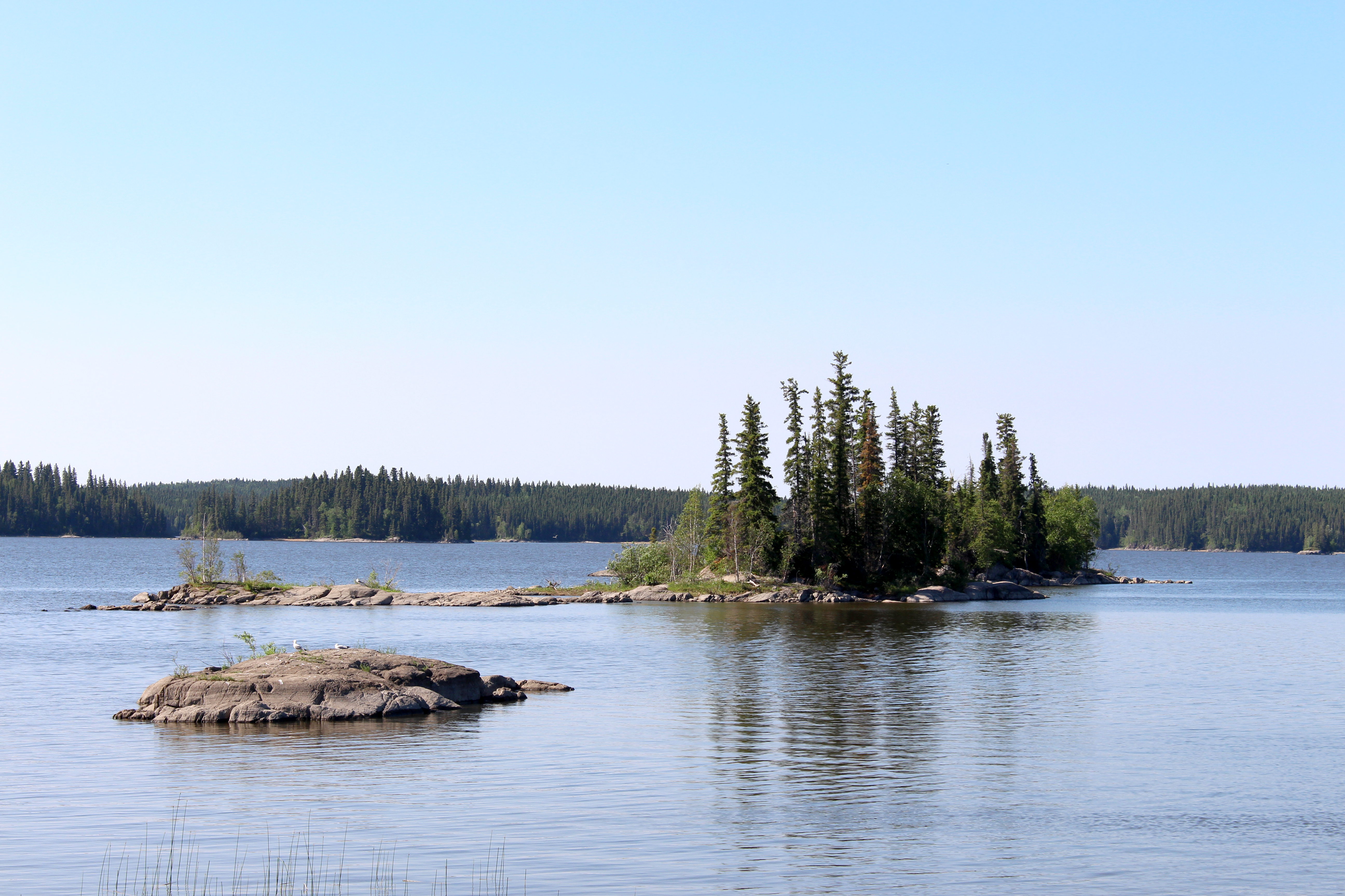 A large lake with small rocky islands and forest behind