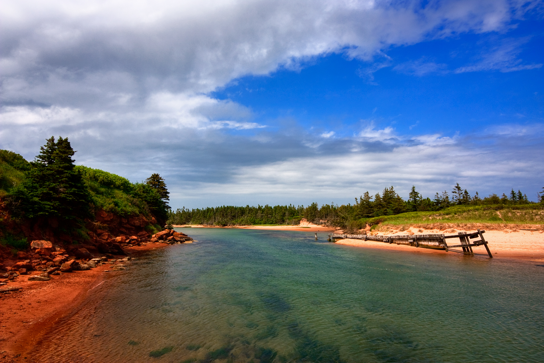 Beach with eroded soft red sandstone cliffs near shore located in Basin Head Provincial Park