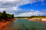 Beach with eroded soft red sandstone cliffs near shore located in Basin Head Provincial Park