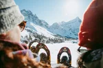 Couple sitting with snowshoes looking out into the mountain scenery