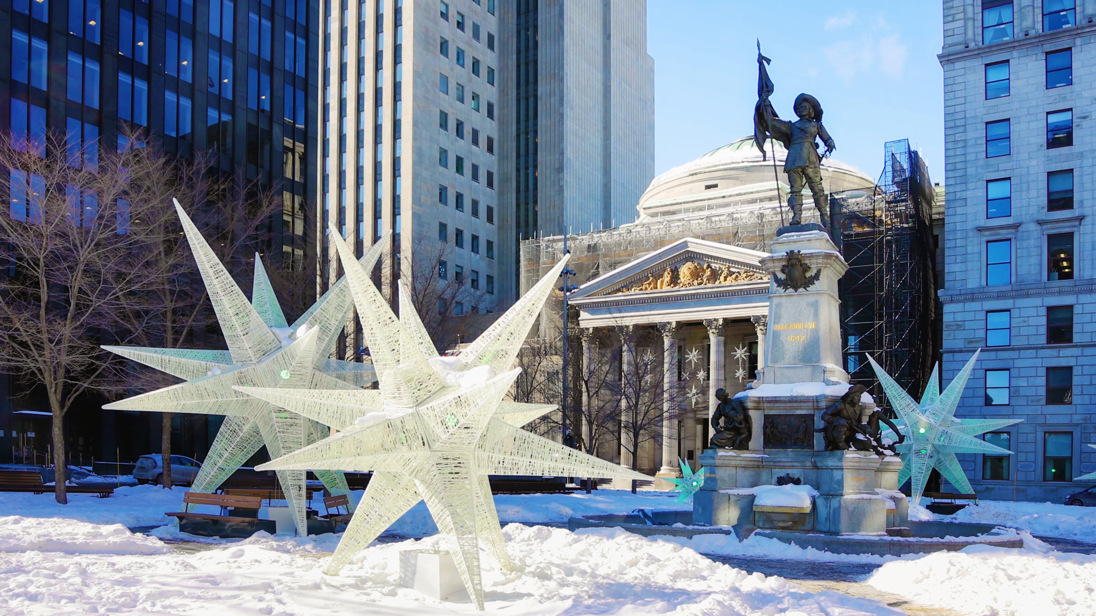 Statue and winter star decorations in Place D'Armes in snowy Montreal