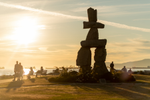 People looking at the sunset at the English Bay Inukshuk in Vancouver