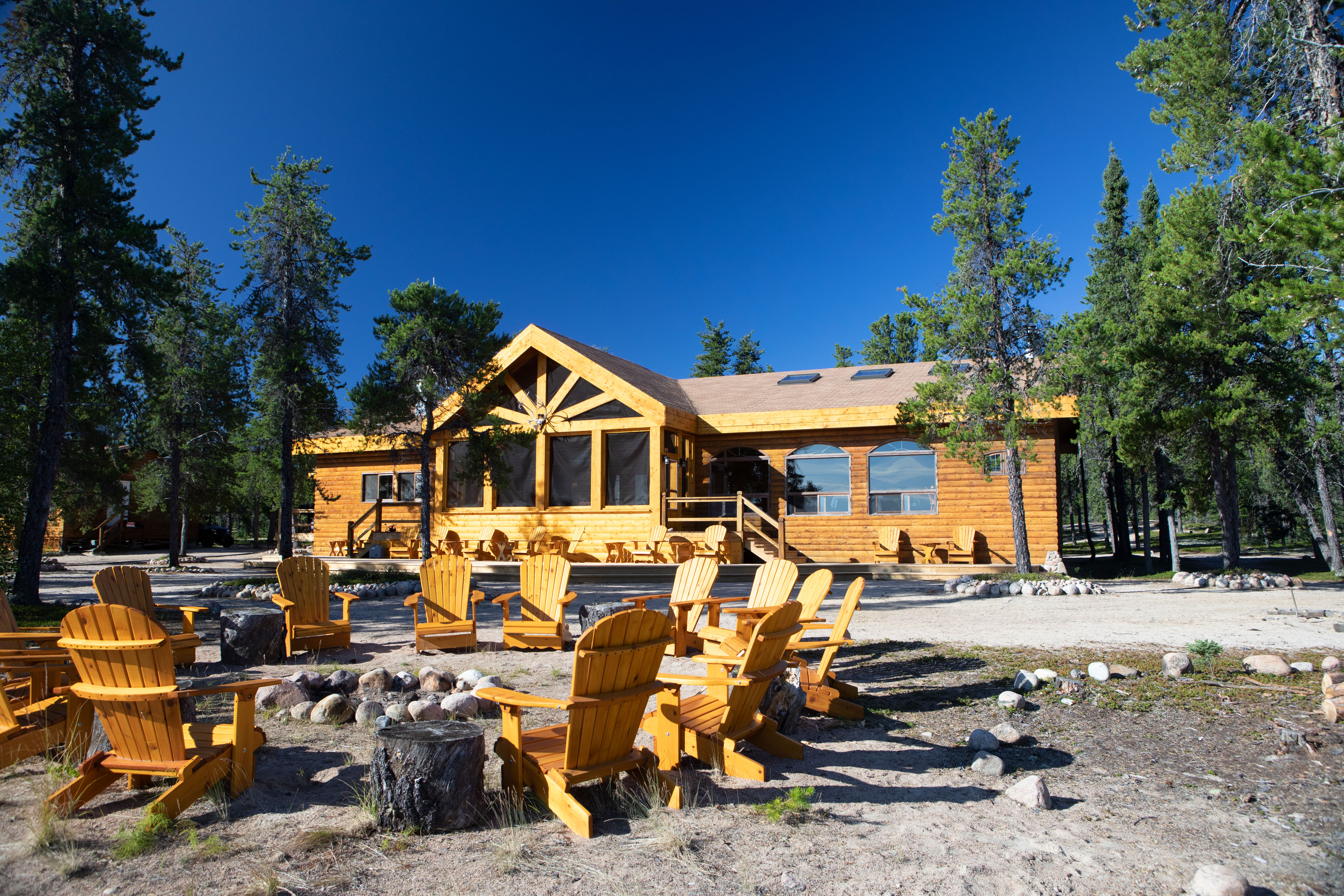 A wooden lodge cabin with a circle of chairs in front of it