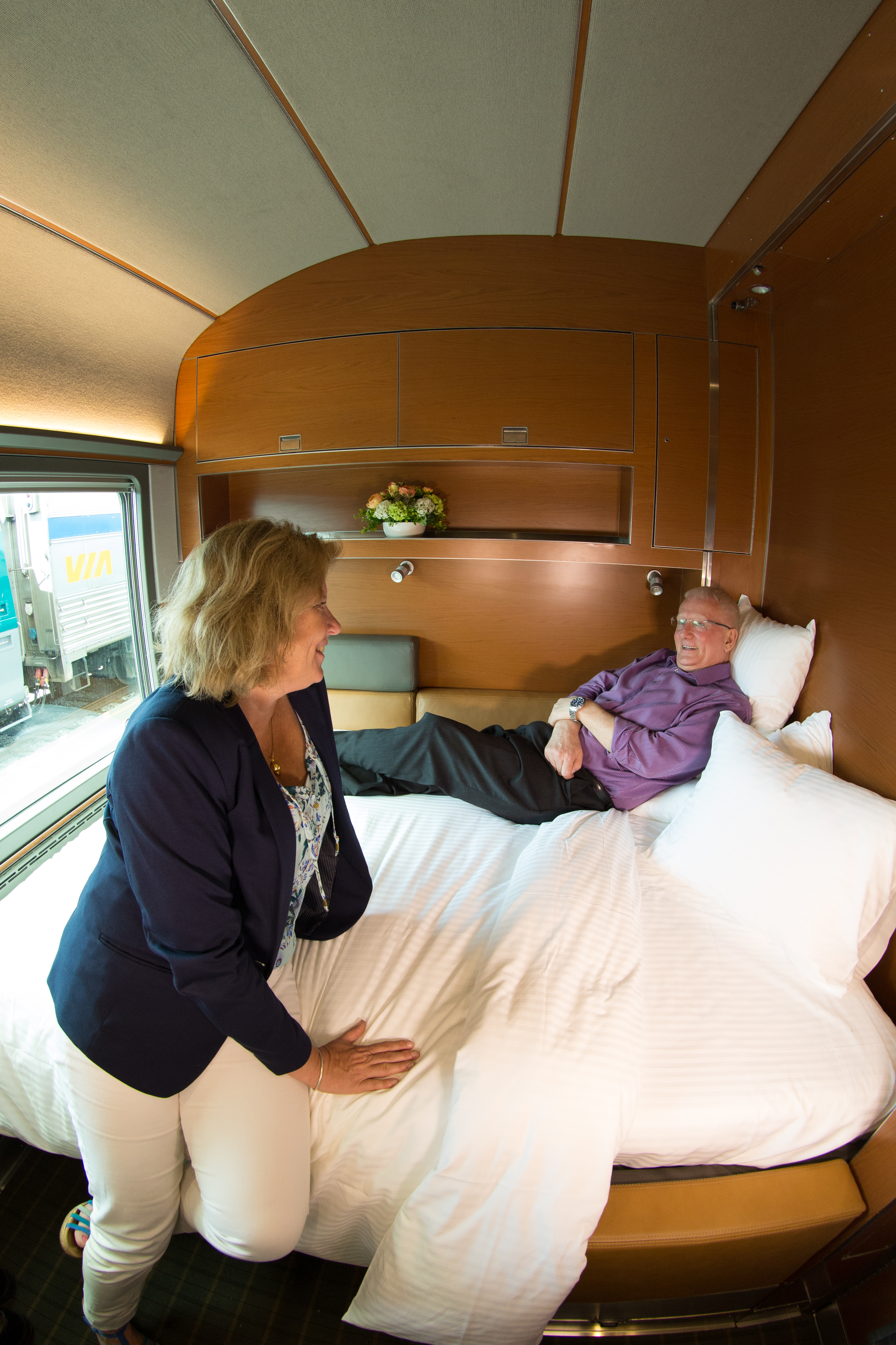 A couple looks at each other while sitting on the bed in the train cabin.