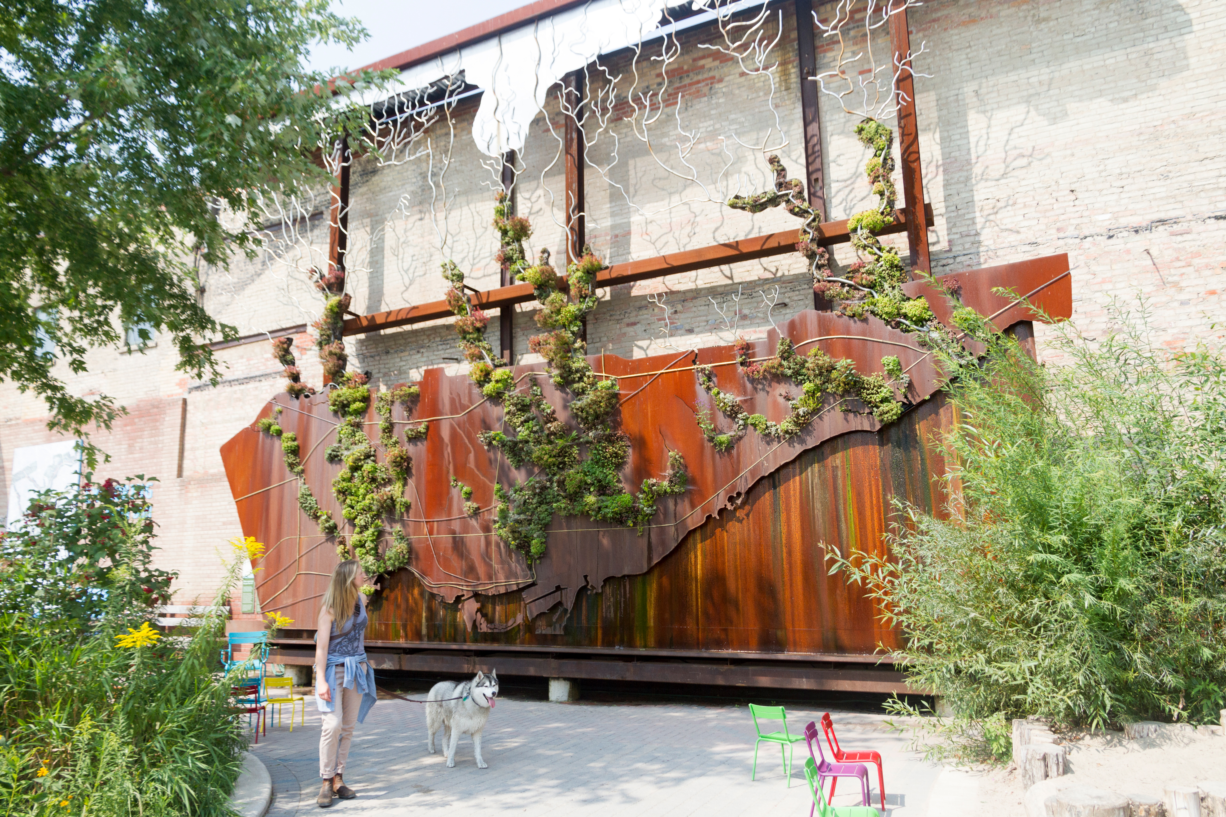  Person walks her dog past a large outdoor living map at Evergreen Brick Works