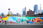 Person walking past a long colourful art mural in Calgary’s East Village