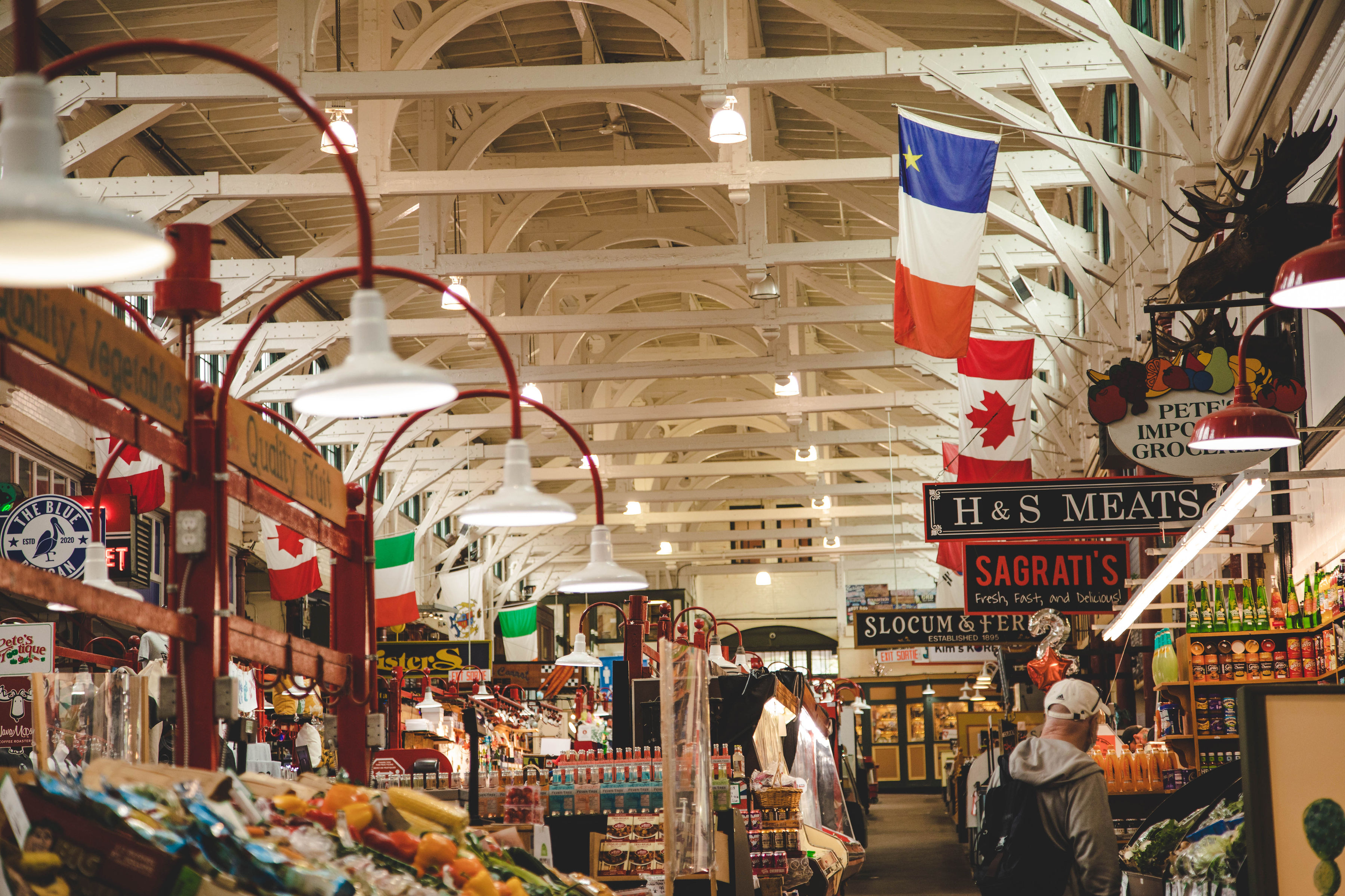 Shopper in old traditional farmers market with structured roof rafters and Mounted Moosehead in Saint John City Market