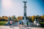 A group of cyclists stop to look at the Sir George-Étienne Cartier Monument with fall colours behind