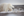 A polar bear looks into the distance and walks along a frozen landscape