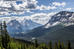 Clouds over the towering mountains and forest in Banff National Park